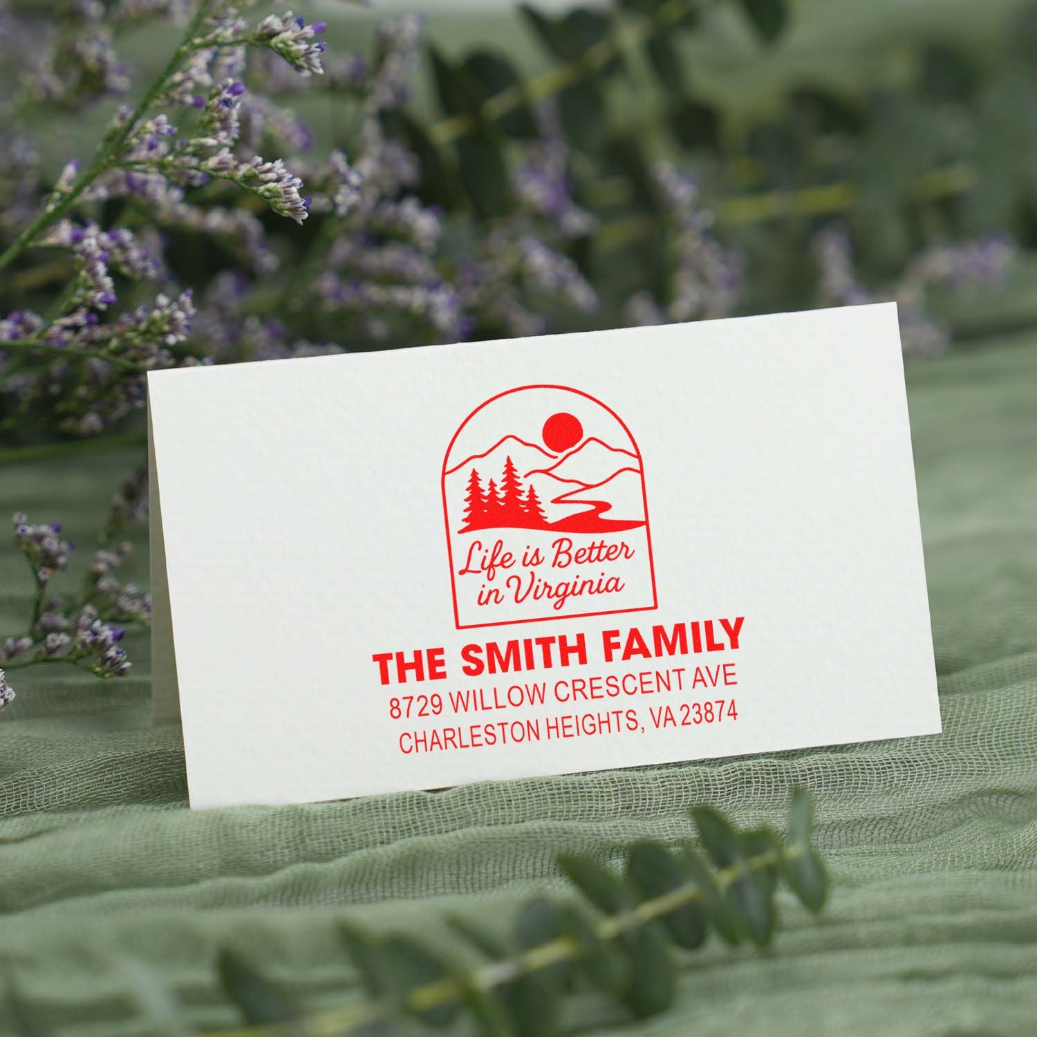 Custom red return address stamp for The Smith Family with Life is Better in Virginia logo, displayed on a white card over green floral fabric.