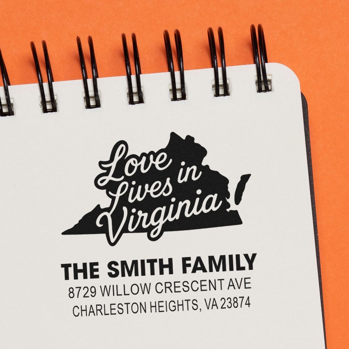 Custom address stamps on a spiral notebook, featuring Love Lives in Virginia and The Smith Family address on an orange background.