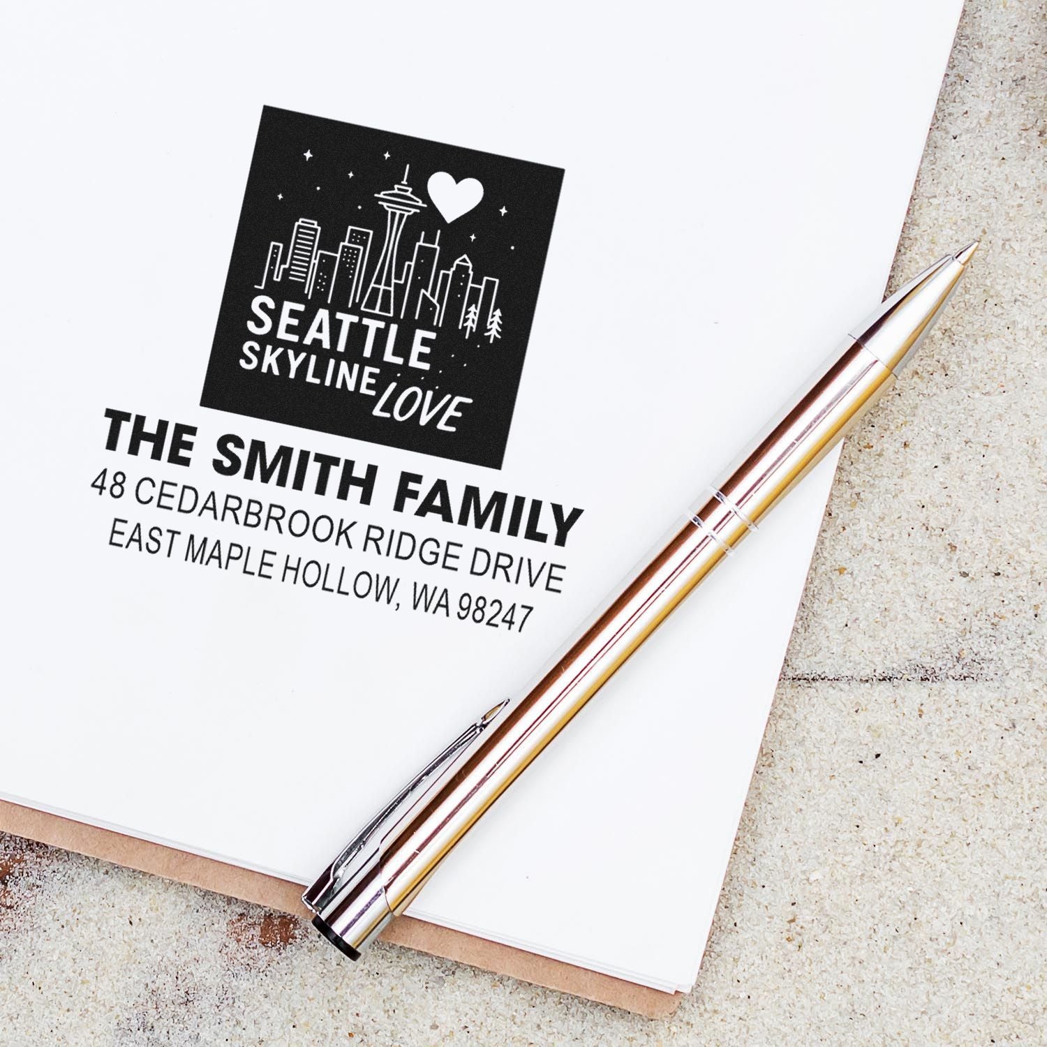 Seattle Skyline Love custom address stamp on white stationery with metallic pen, featuring The Smith Family name and Seattle skyline design