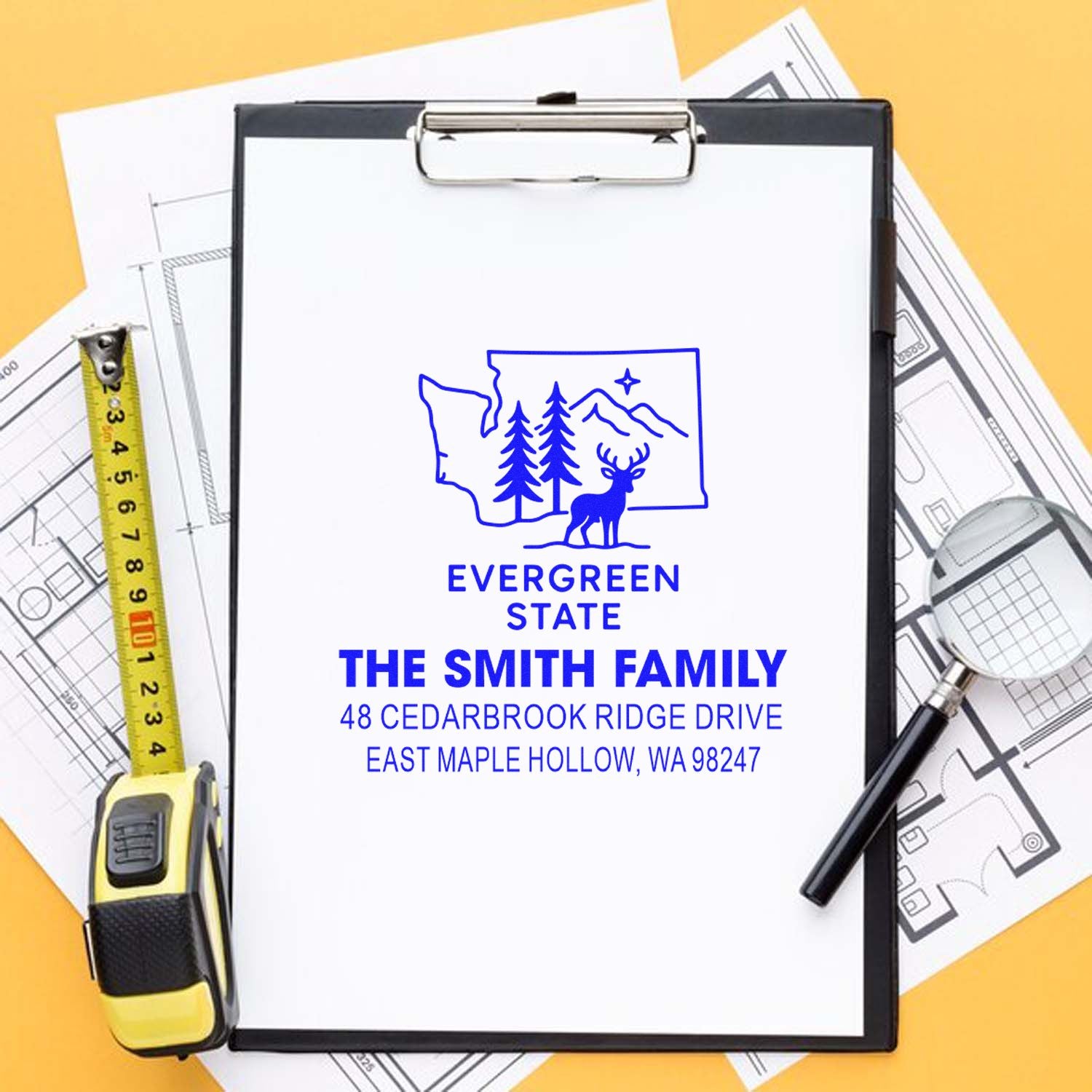 Custom address stamp for The Smith Family on a clipboard with house plans, tape measure, pen and magnifying glass, featuring Evergreen State design.