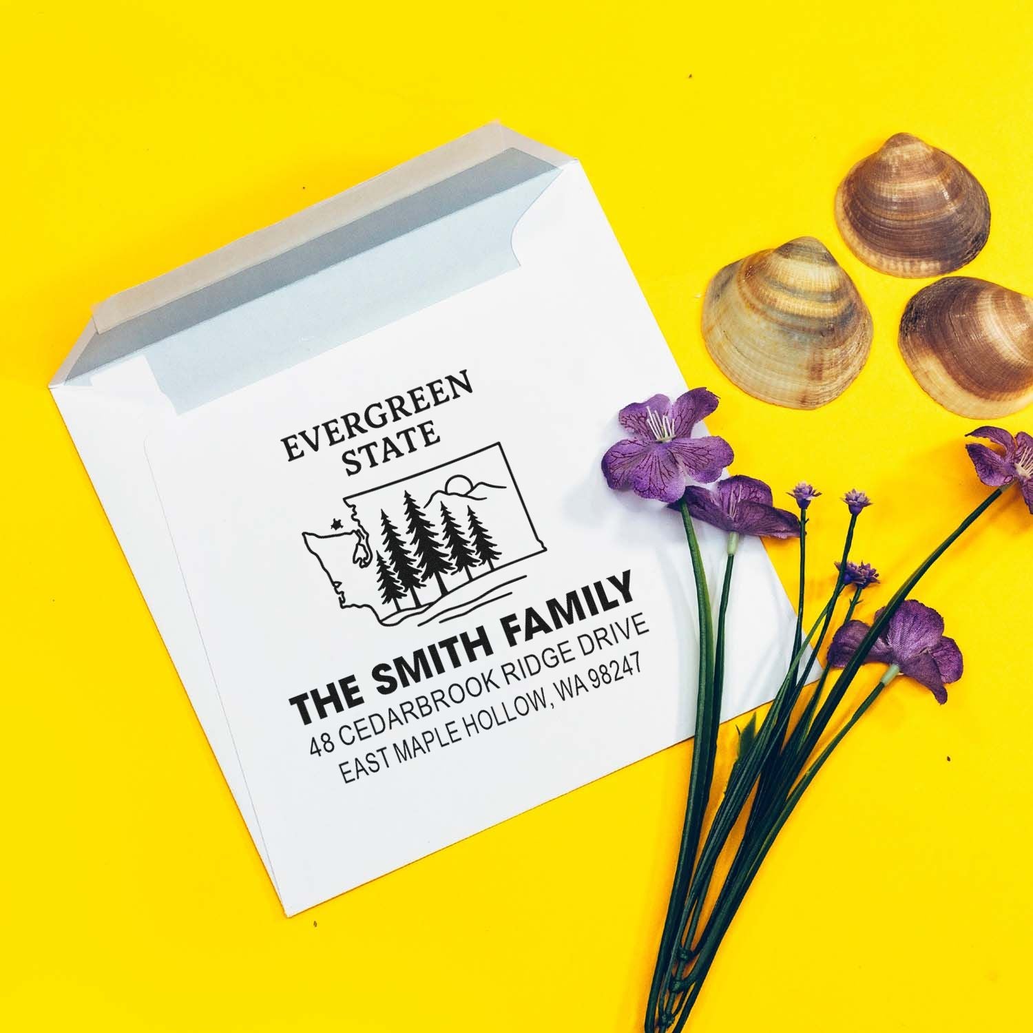 Personalized address stamp for The Smith Family on a white envelope, styled with seashells and purple flowers on a bright yellow background.