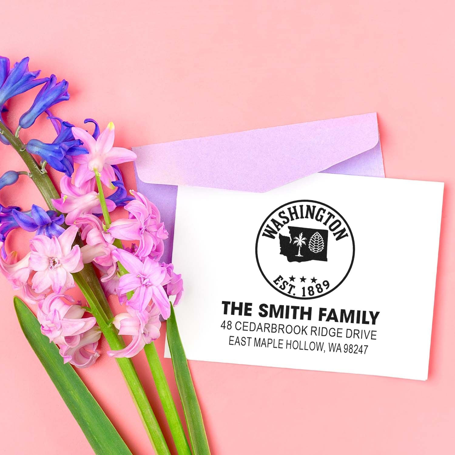 Custom Washington return address stamp on white envelope with lavender liner, styled with pink and purple hyacinths on a pink background.