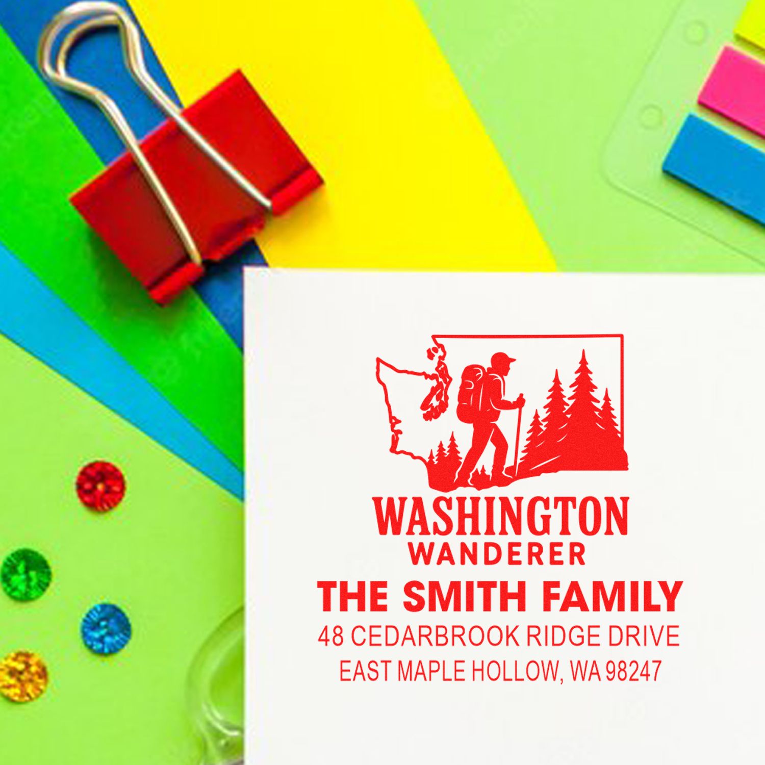 Custom Washington Wanderer address stamp with hiker and pine trees on colorful stationery, clipped with a red binder clip.