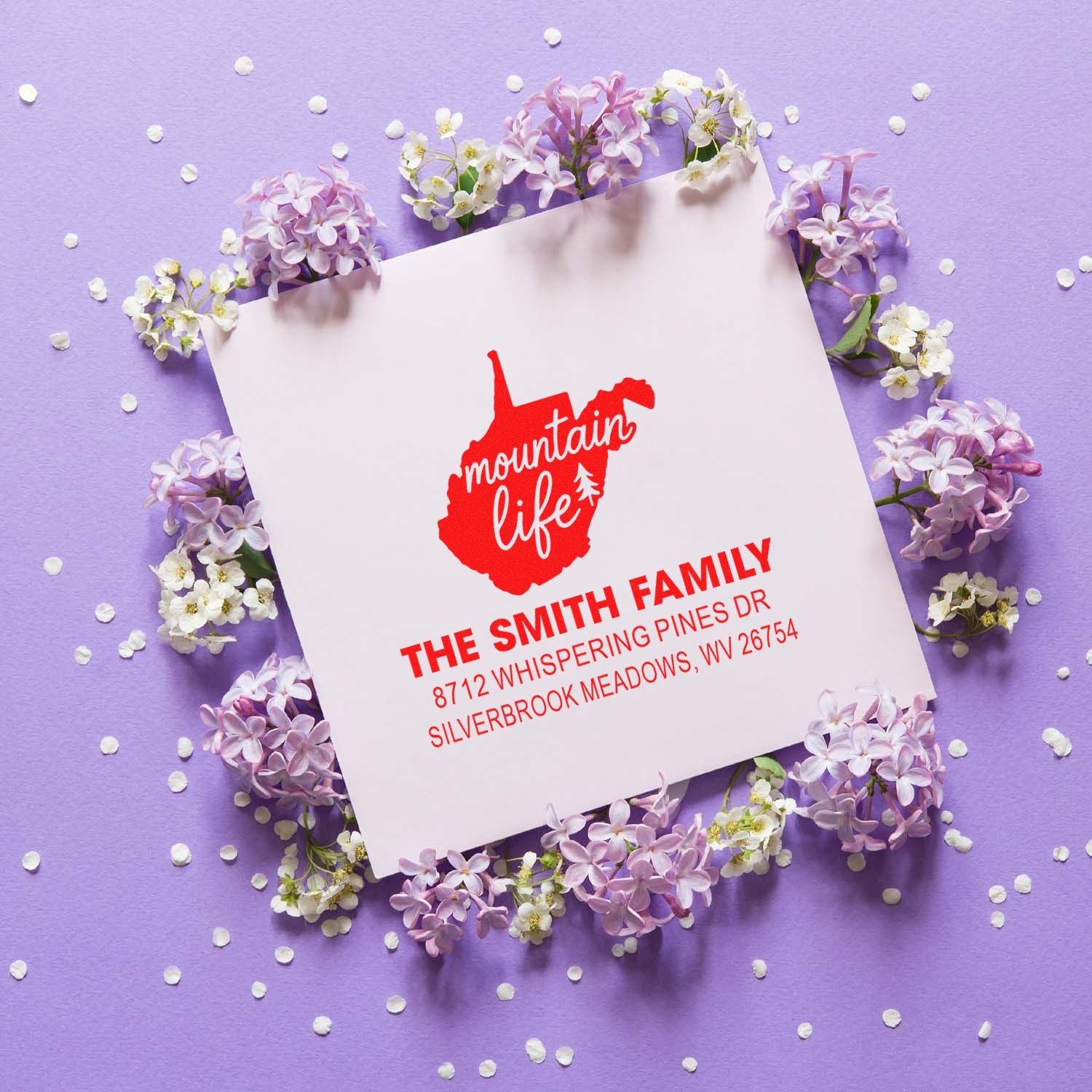 Custom mountain life address stamp with The Smith Family name and address on white card, surrounded by lilac flowers on purple background.