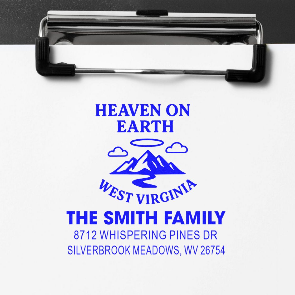Personalized blue self-inking address stamp on paper, reading Heaven on Earth West Virginia, The Smith Family, with mountains and address details.