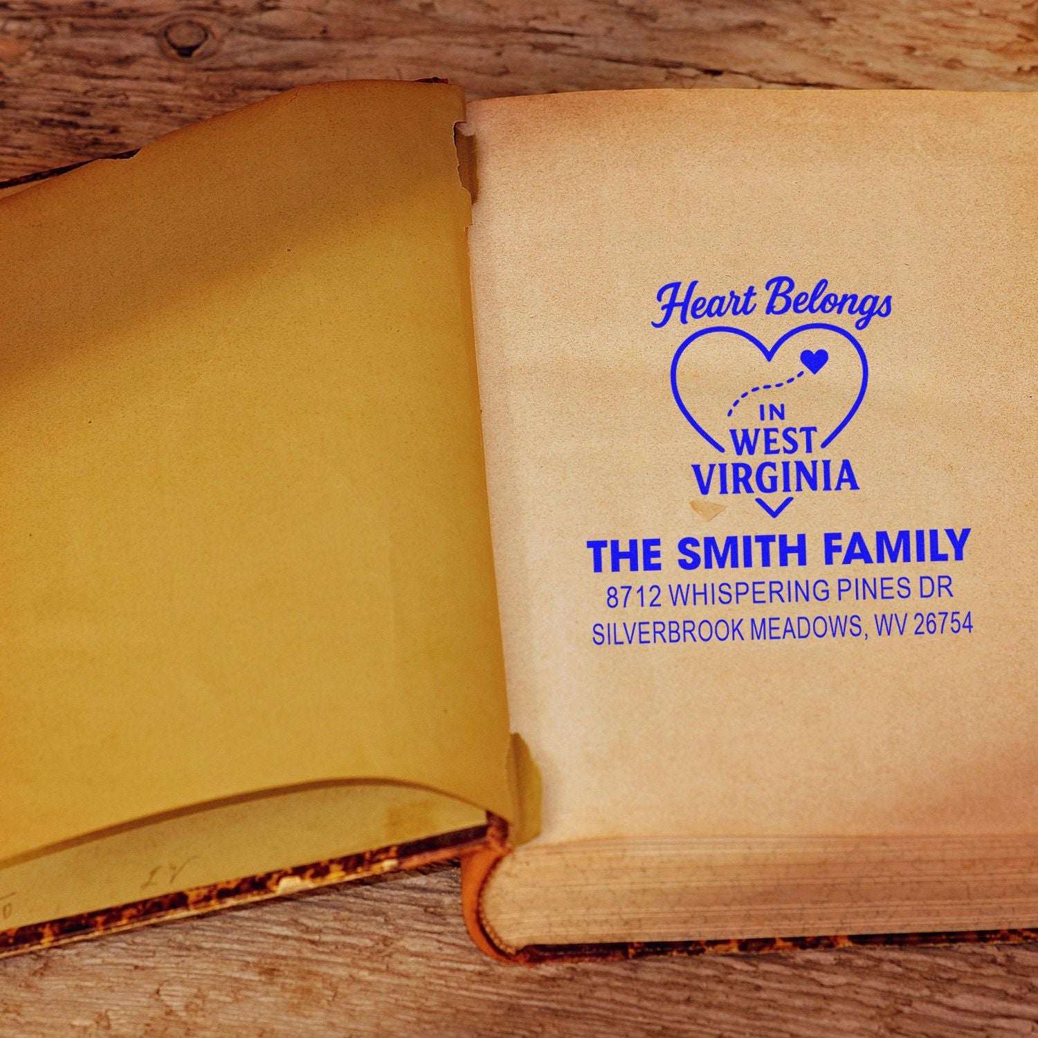 Custom return address stamp with heart design on open book pages, reading Heart Belongs in West Virginia for The Smith Family.