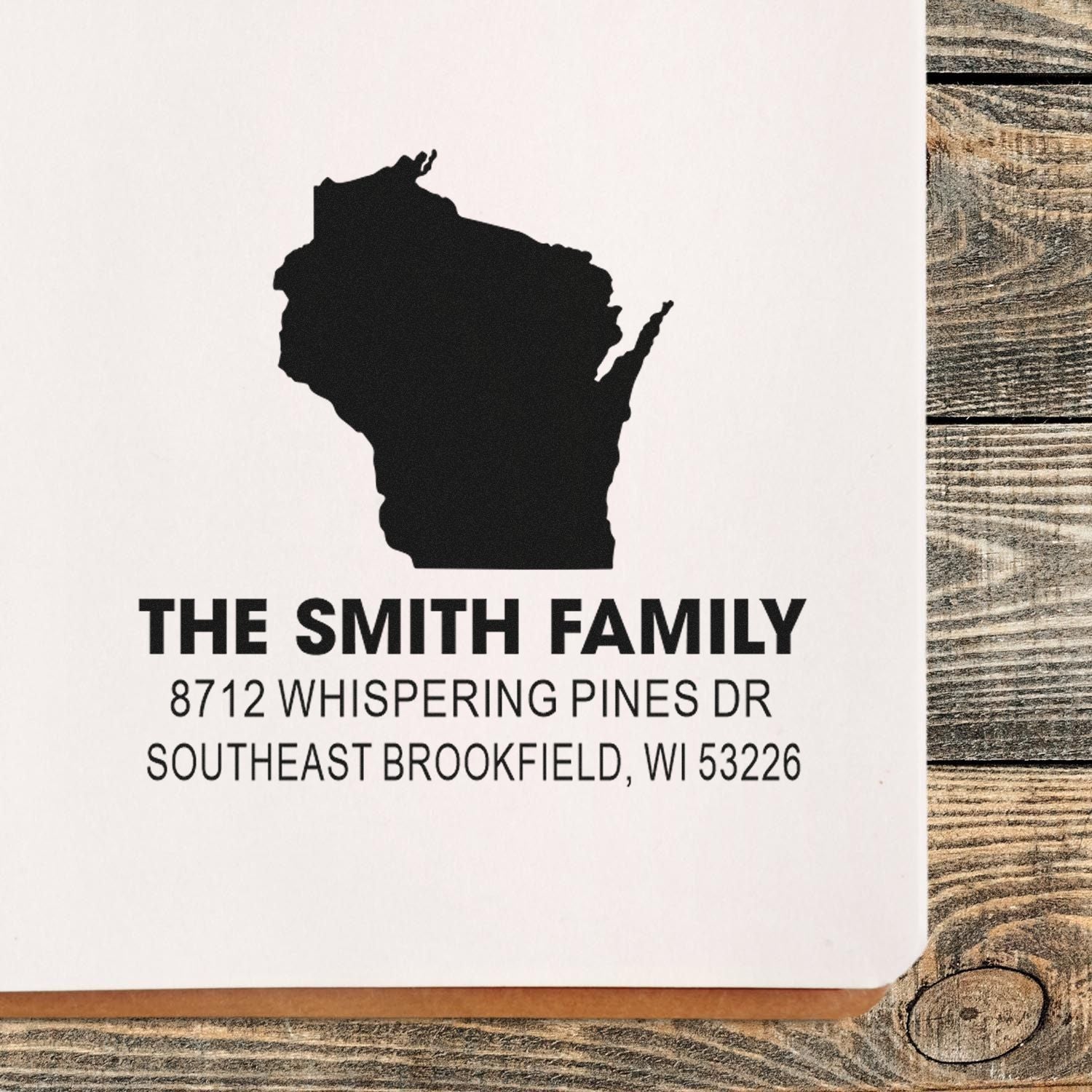 Custom address stamp for The Smith Family with Wisconsin silhouette, shown on white paper over a rustic wood table.