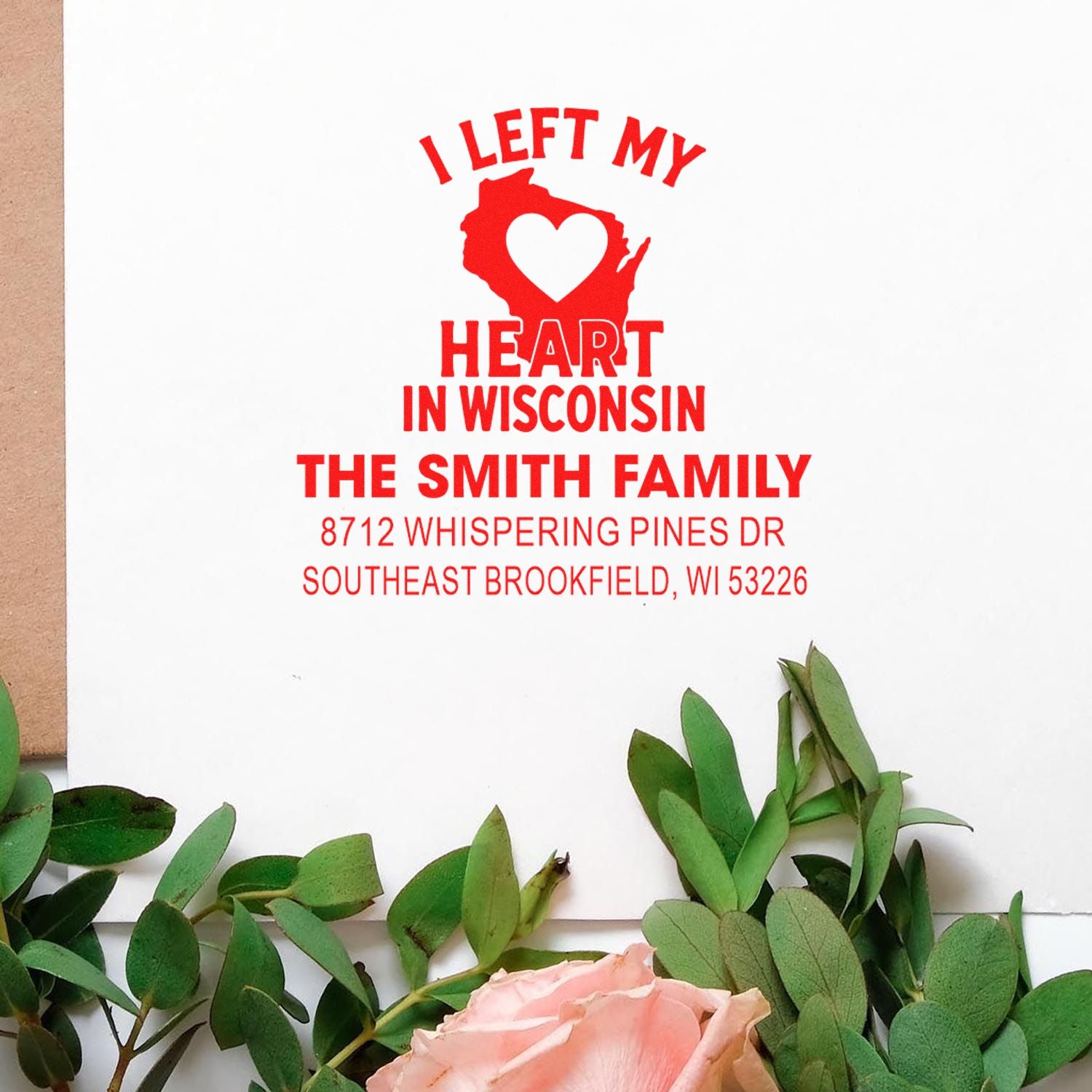 Custom return address stamp in red, featuring I Left My Heart in Wisconsin, Wisconsin heart graphic, and Smith Family address on white paper with greenery.