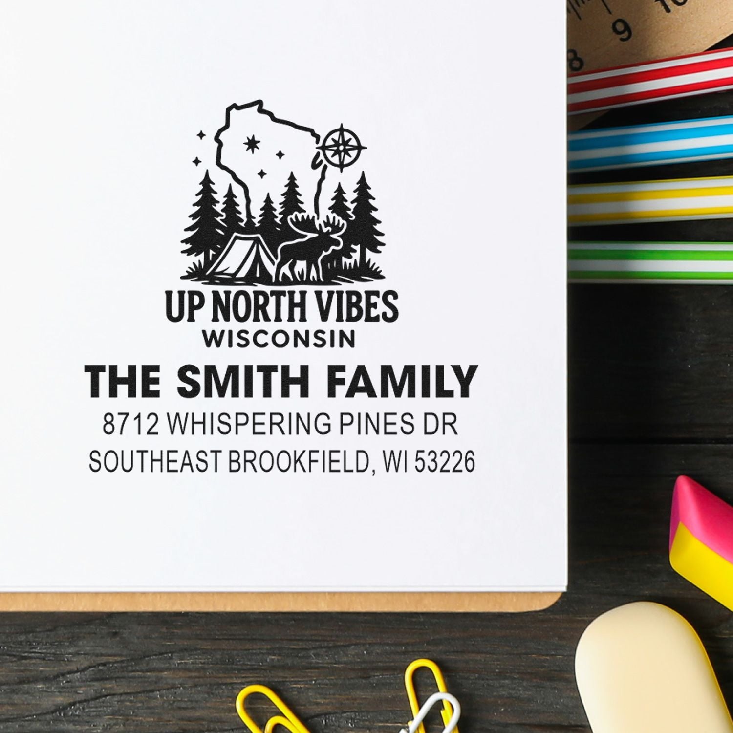 Personalized address stamp with Up North Vibes Wisconsin camping design for The Smith Family, shown on white paper with ink pads and office supplies.
