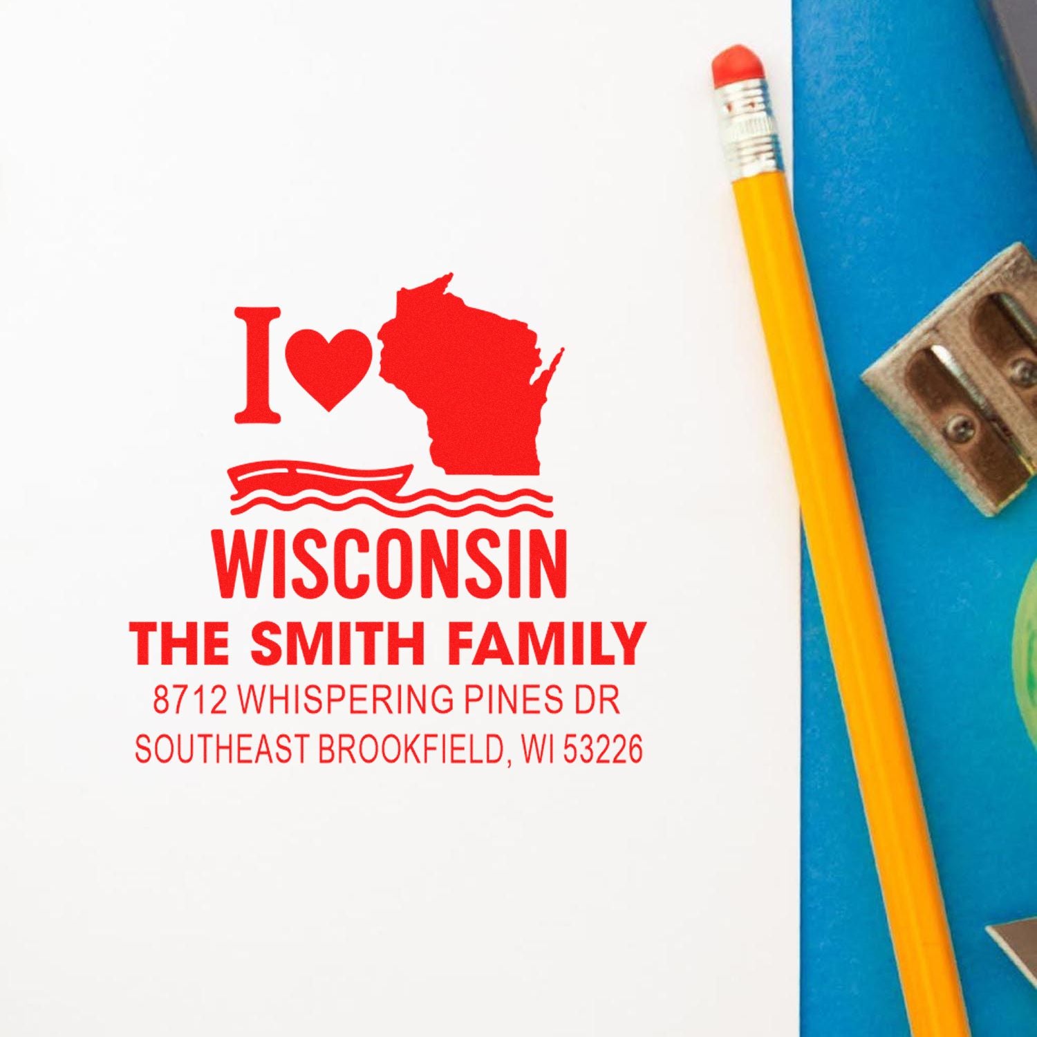 Personalized Wisconsin address stamp with I ? Wisconsin design, Smith family name and Brookfield, WI address on white paper beside a pencil.