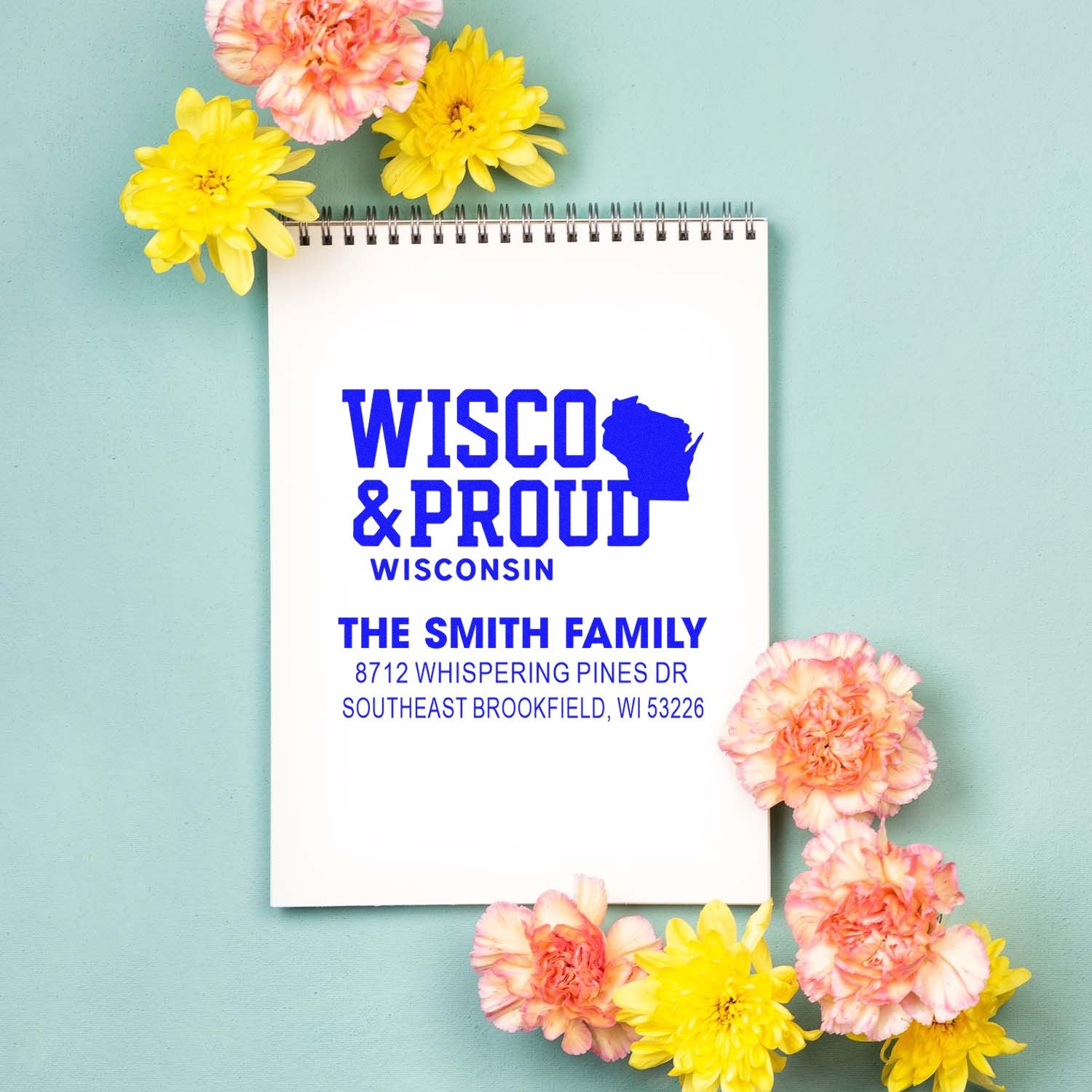 Wisconsin Proud custom address stamp with The Smith Family name and Brookfield, WI address, displayed on a spiral notebook with flowers.