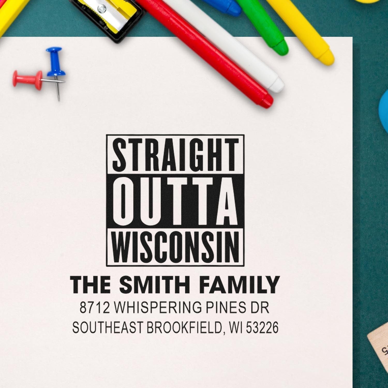 Custom return address stamp reading Straight Outta Wisconsin for The Smith Family, with colorful pens and push pins on a desk.