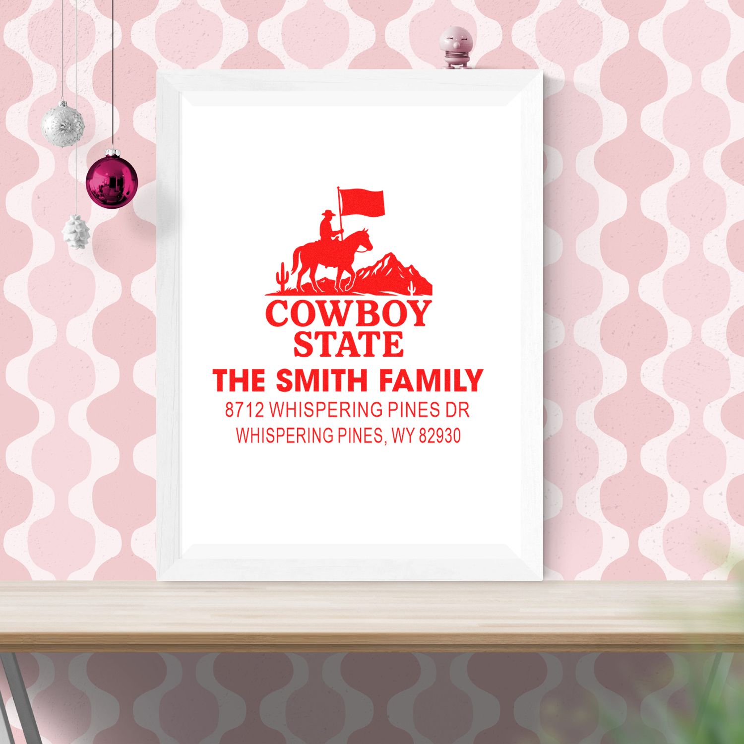 Custom cowboy state family address stamp design in a white frame on pink patterned wall, featuring rider, flag, and red text for The Smith Family.