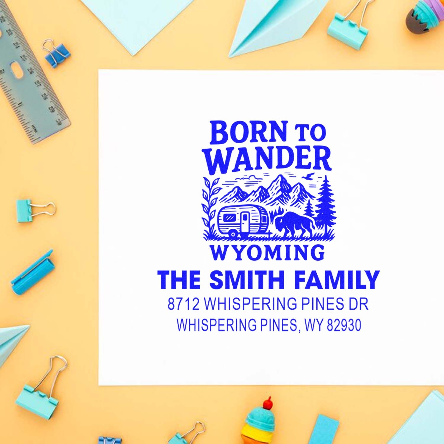 Custom Wyoming address stamp with Born to Wander design, featuring mountains, trailer and bison on a white card with school supplies.