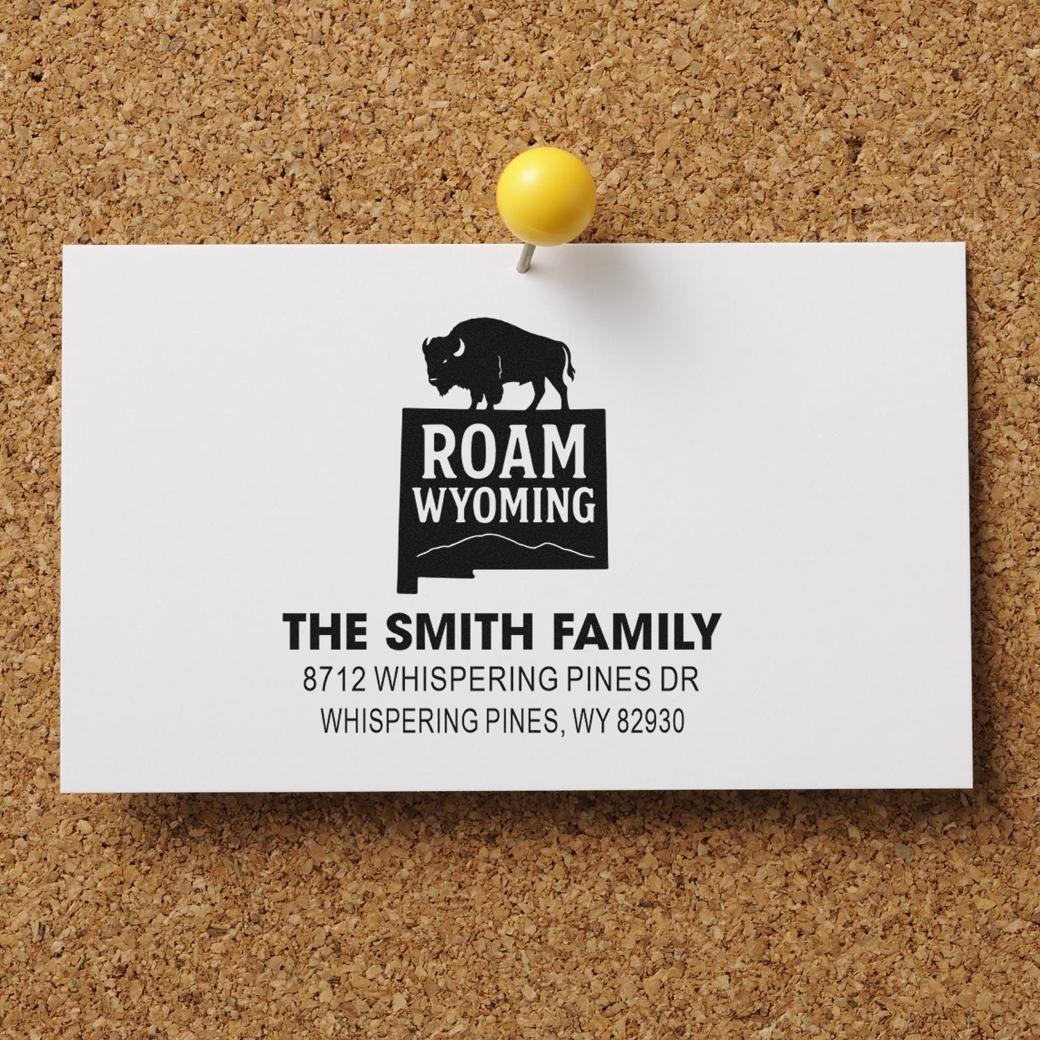 Custom family address stamp on corkboard, featuring Roam Wyoming bison logo and Smith family address pinned with a yellow tack.
