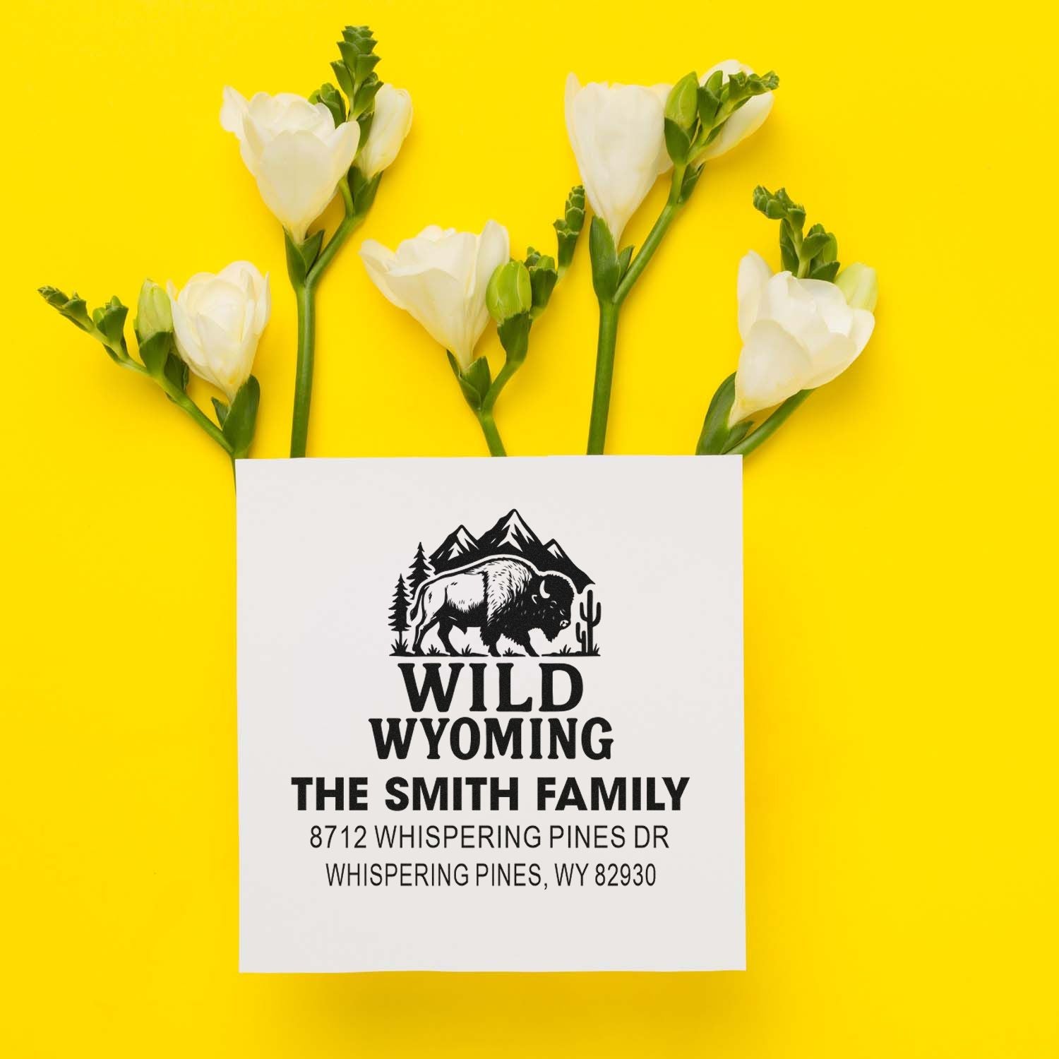 Custom Wild Wyoming family address stamp with bison logo and return address, styled with white flowers on a bright yellow background.