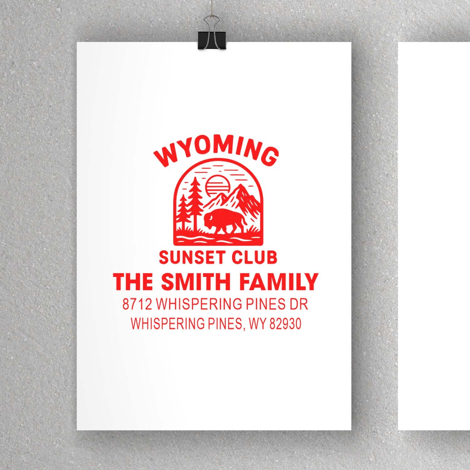 Wyoming Sunset Club custom address stamp with bison, mountains and pine trees, clipped on white paper against a gray background.