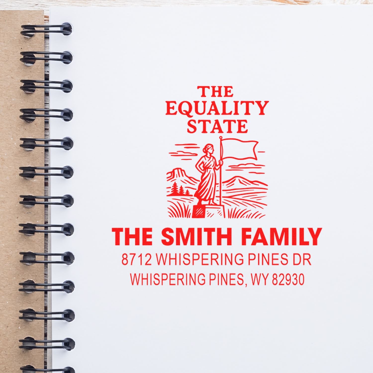 Red custom return address stamp on a spiral notebook page, reading The Equality State for The Smith Family with Wyoming landscape and flag design.