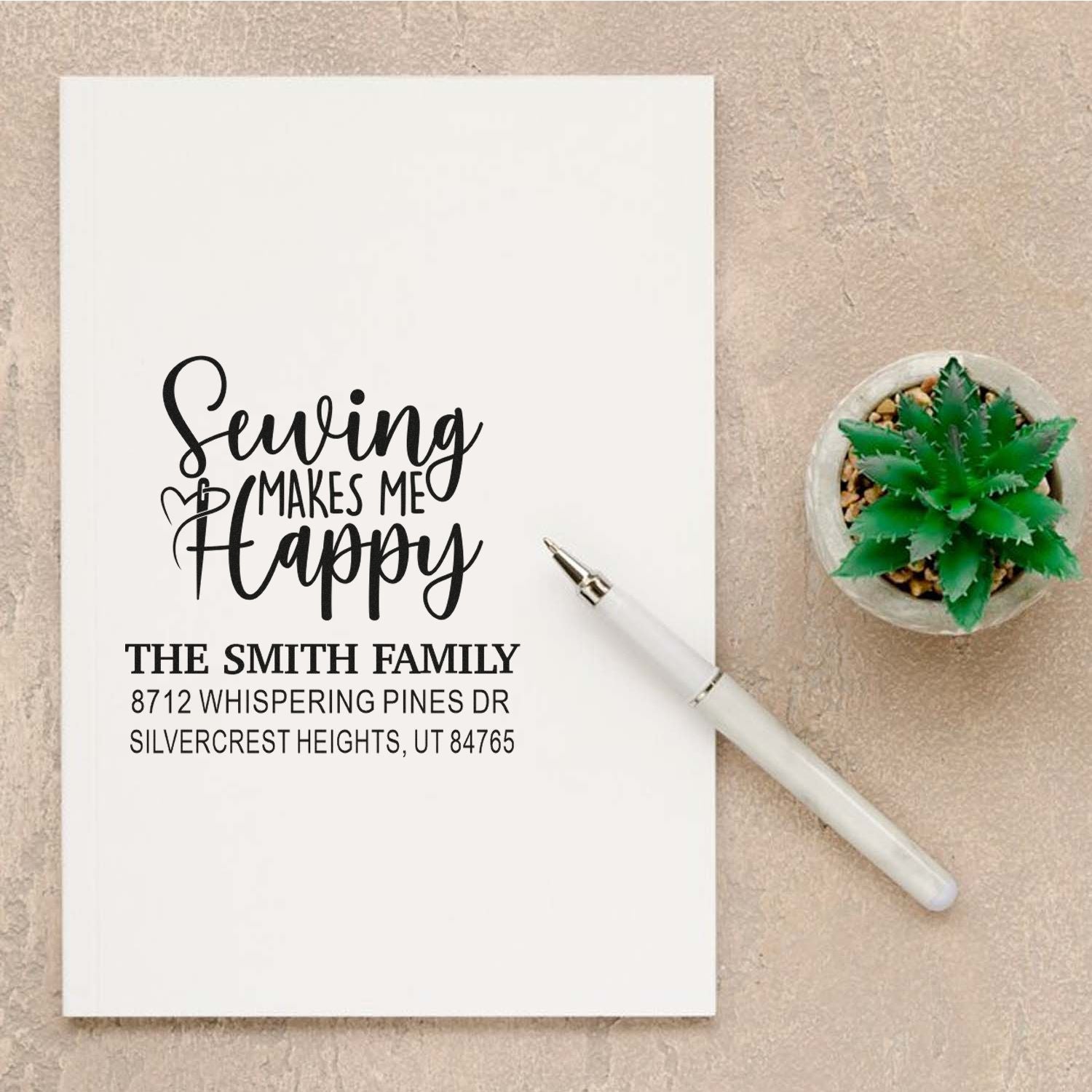 Custom address stamp for The Smith Family with Sealing Makes Me Happy design, shown beside a white pen and potted succulent on a beige background.