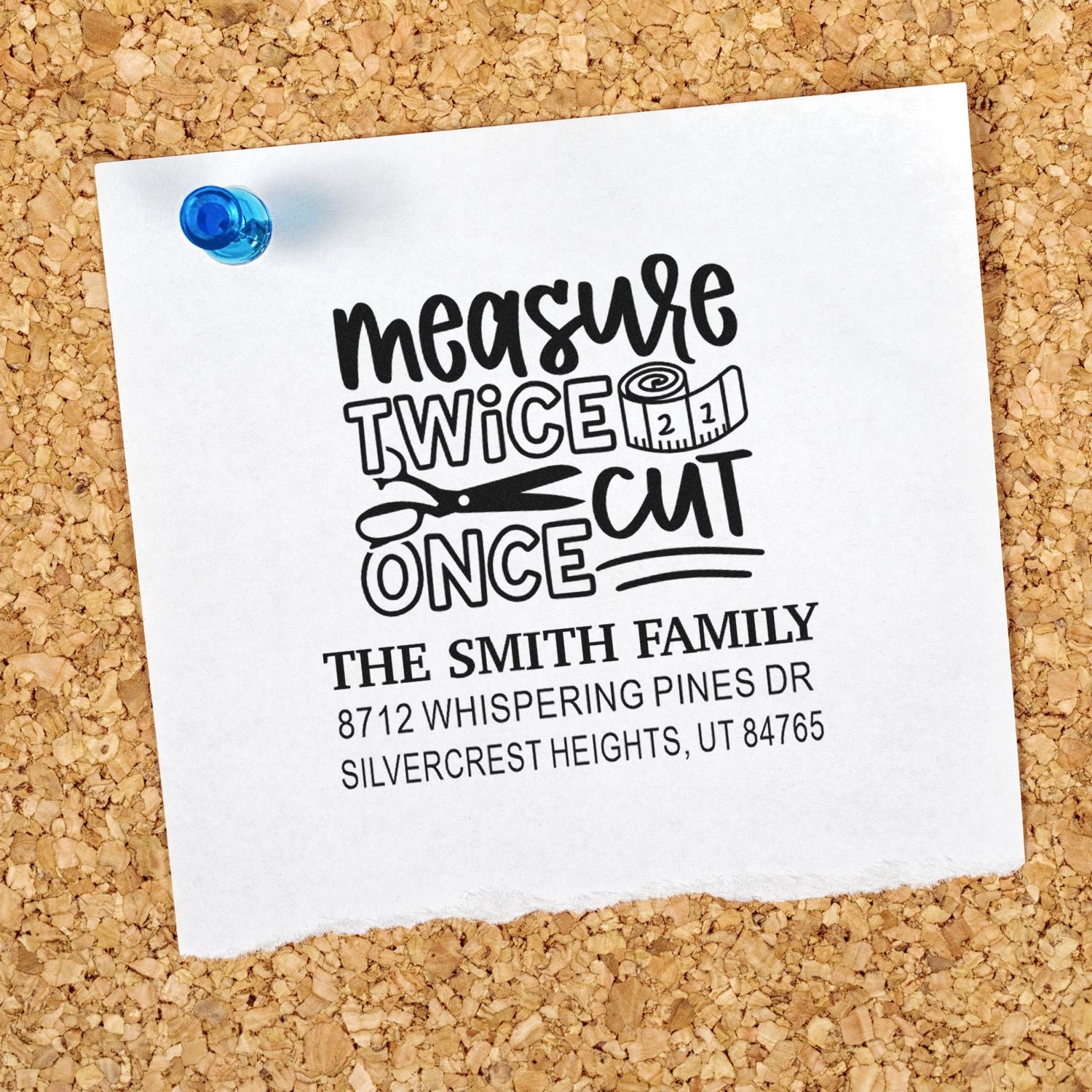 Personalized address stamp on white paper pinned to corkboard, featuring measure twice cut once, scissors, tape measure, and The Smith Family.