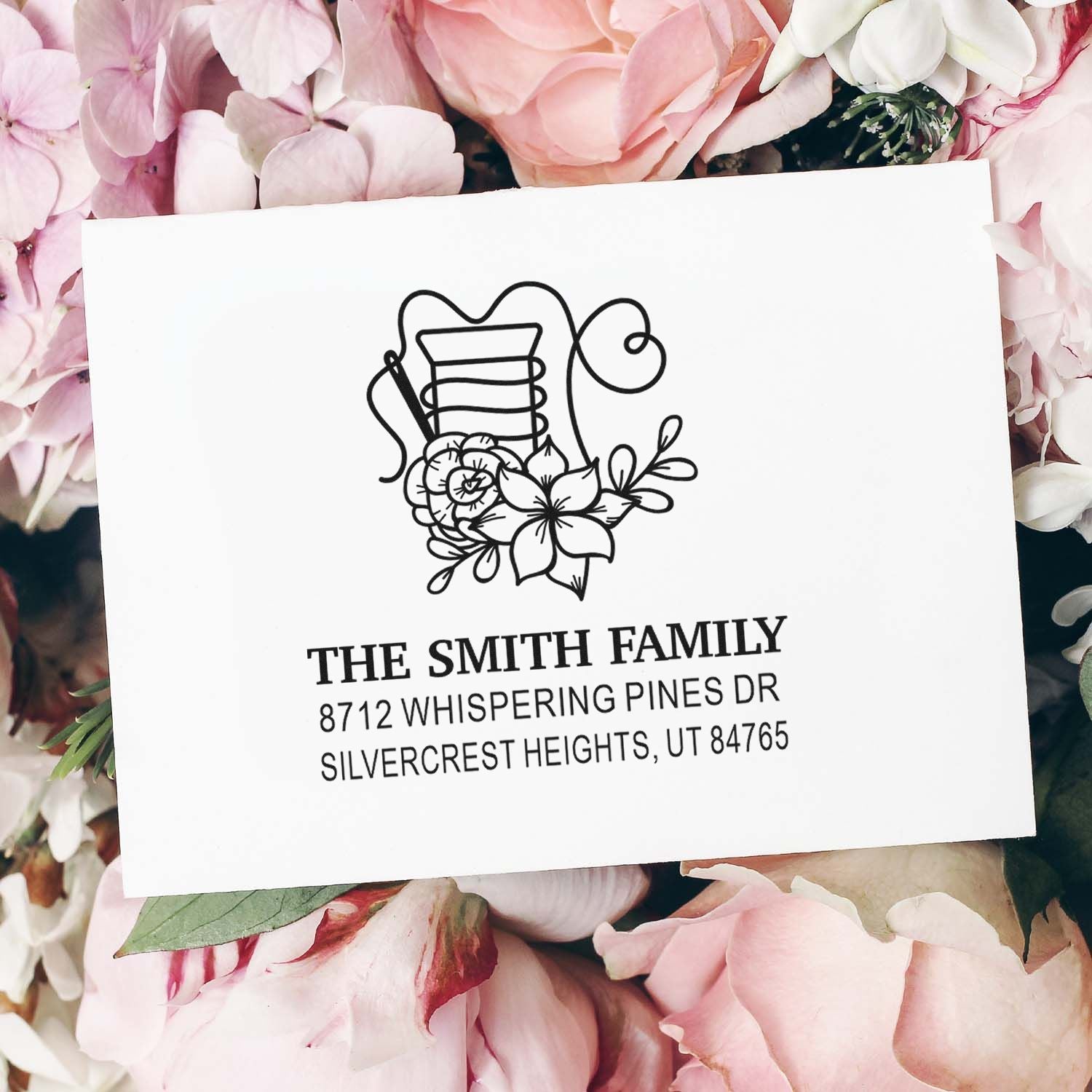 Personalized floral address stamp for The Smith Family, featuring black botanical artwork and a return address on a white card surrounded by pink flowers.