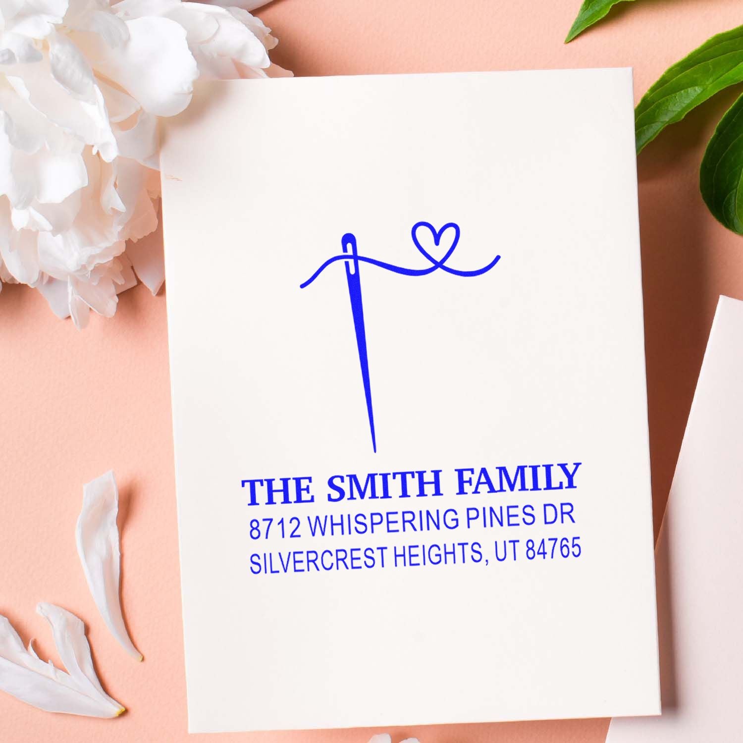Custom return address stamp with heart monogram and The Smith Family address on white card, styled with flowers and green leaves.