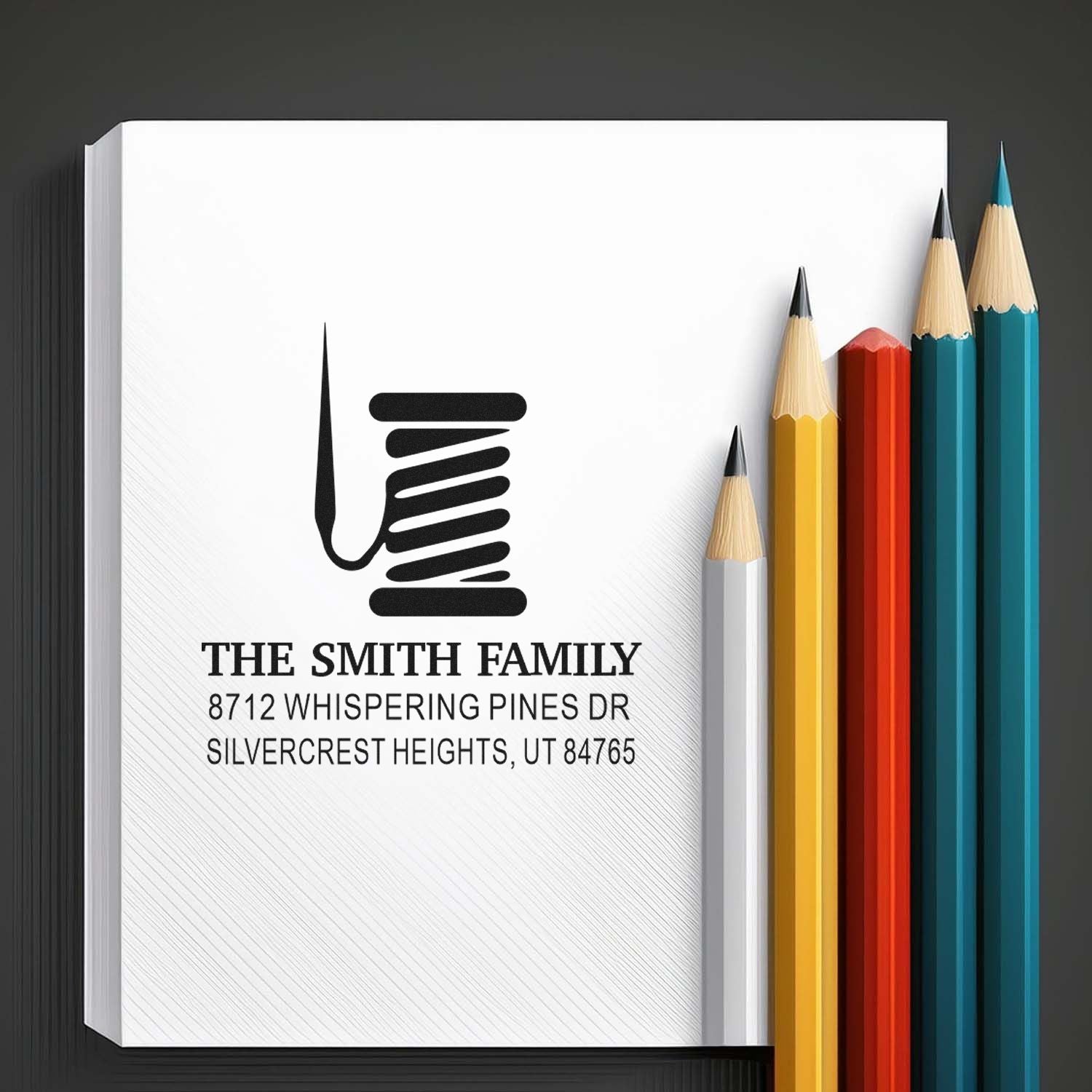 Custom family address stamp for The Smith Family with home address, displayed beside colorful pencils on a dark background.