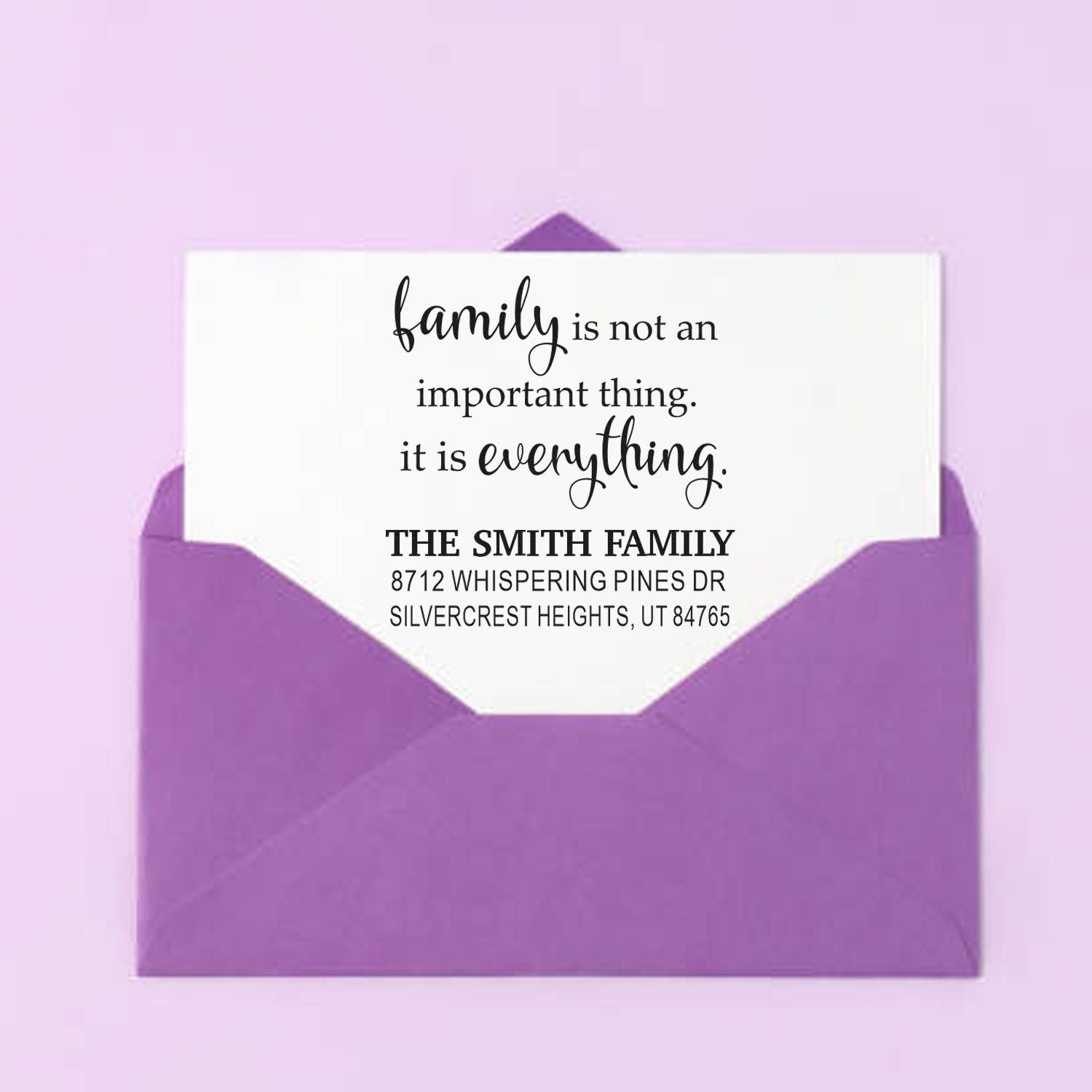 Custom family return address stamp with family is everything quote, shown in a purple envelope on a pastel pink background.