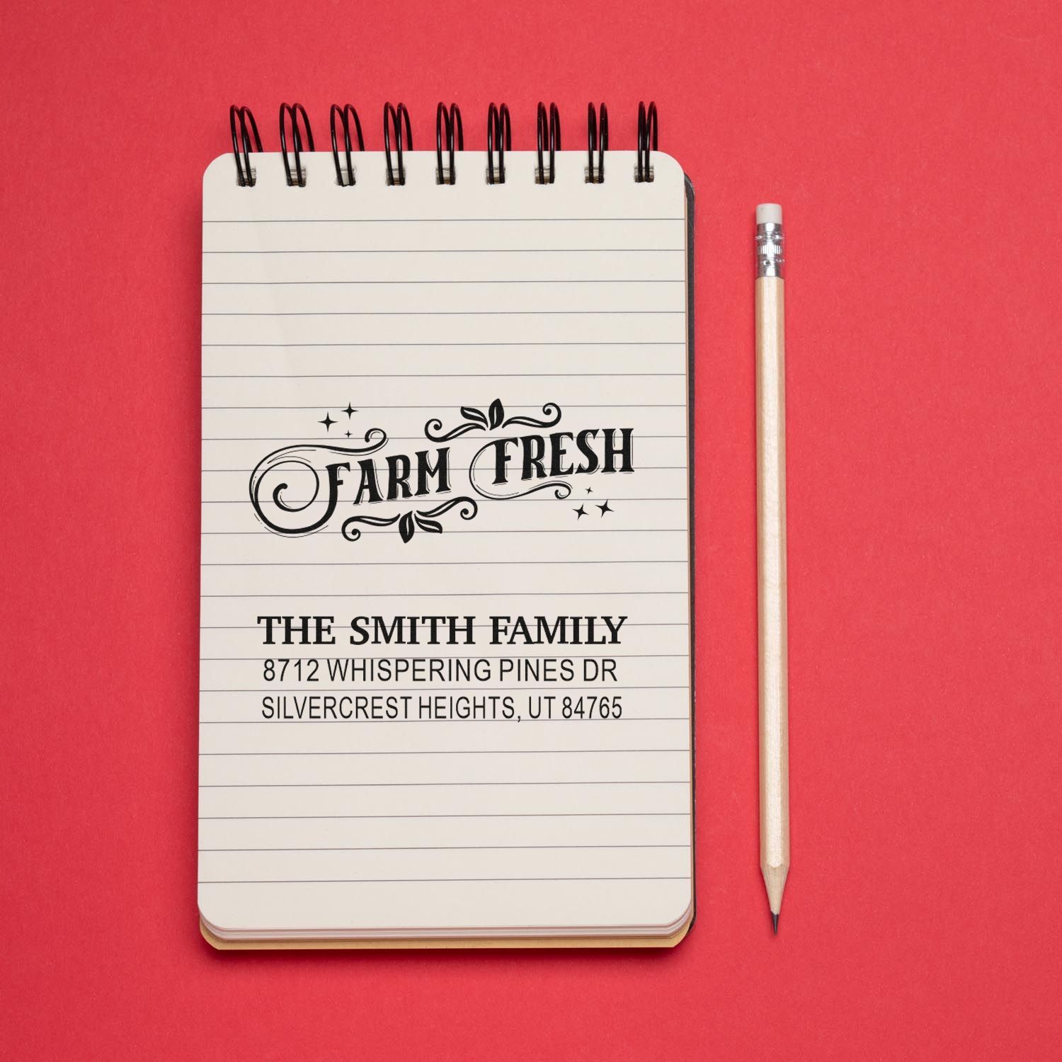 Custom Farm Fresh address stamp on lined notebook beside a pencil, showing The Smith Family and Silvercrest Heights address on a red background.