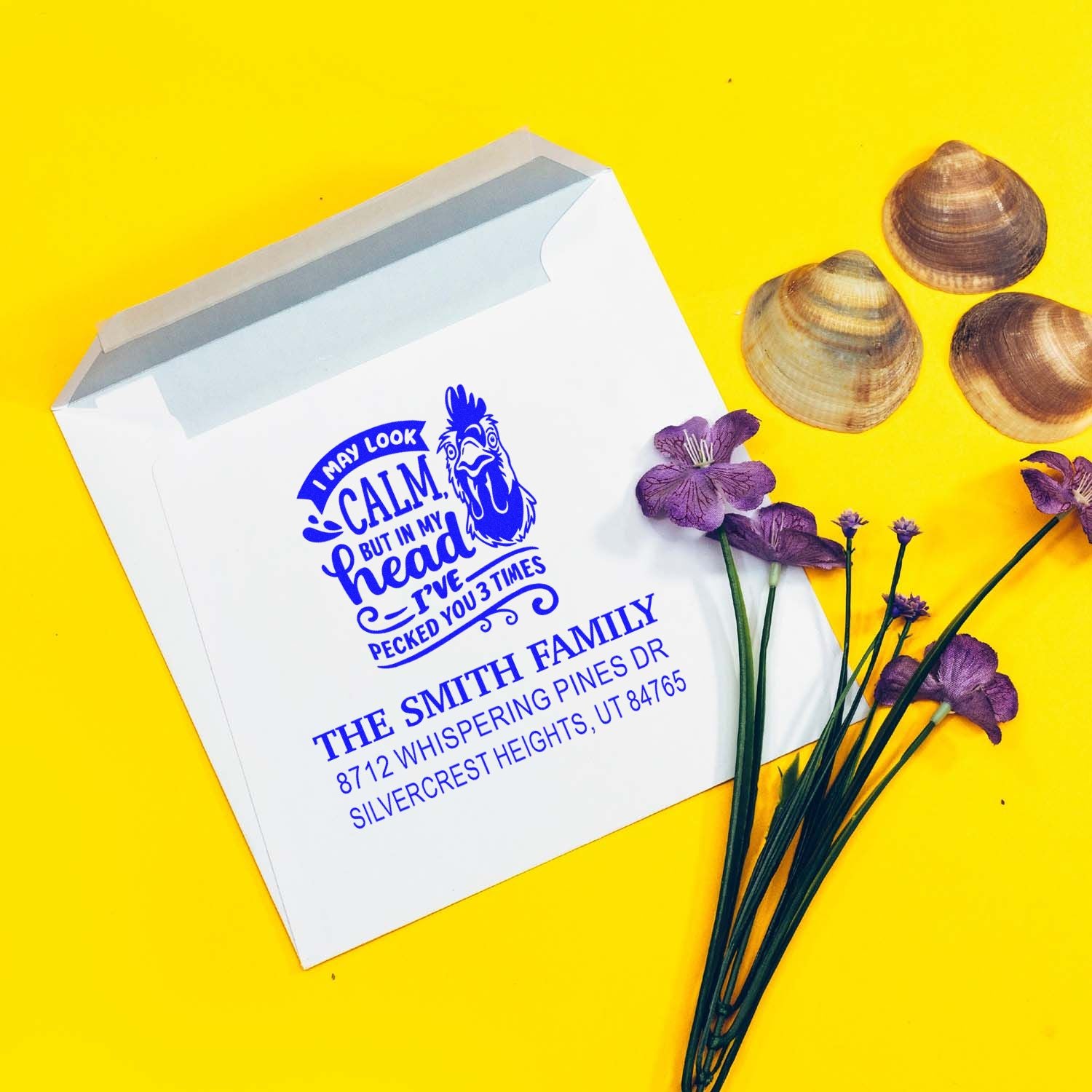 Custom blue chicken address stamp on a white envelope, styled with purple flowers and seashells on a bright yellow background.