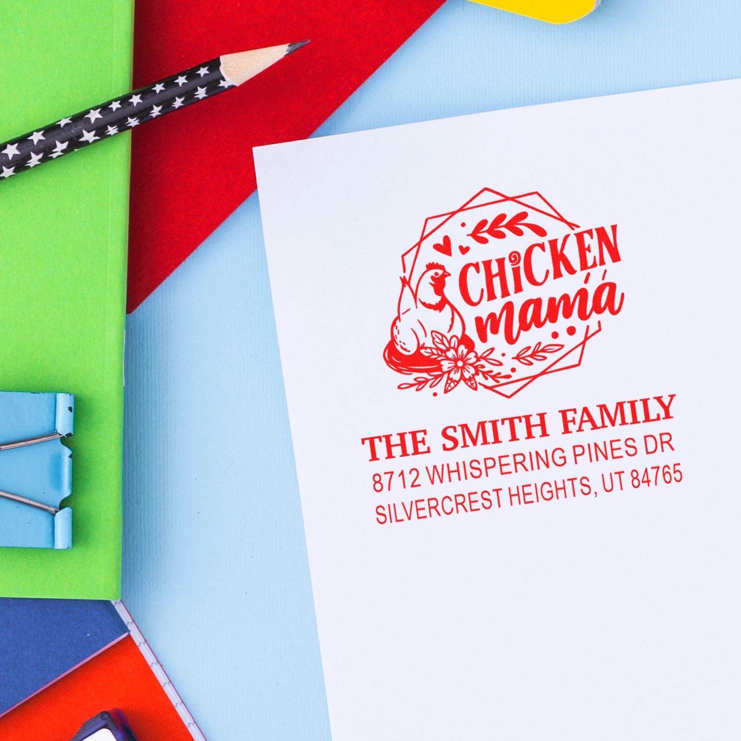 Personalized Chicken Mama address stamp on white paper, surrounded by colorful stationery and a star-pattern pencil on a bright desktop.