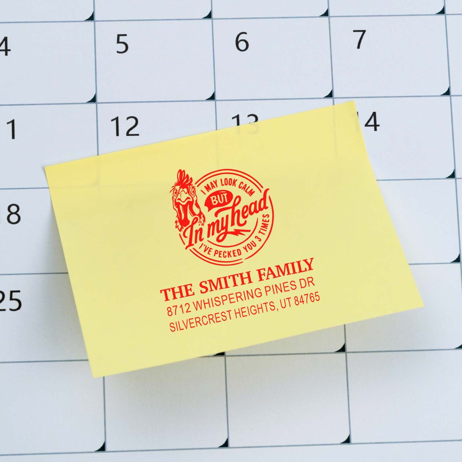 Custom address stamp on a yellow note over a wall calendar, featuring a rooster design and The Smith Family address.