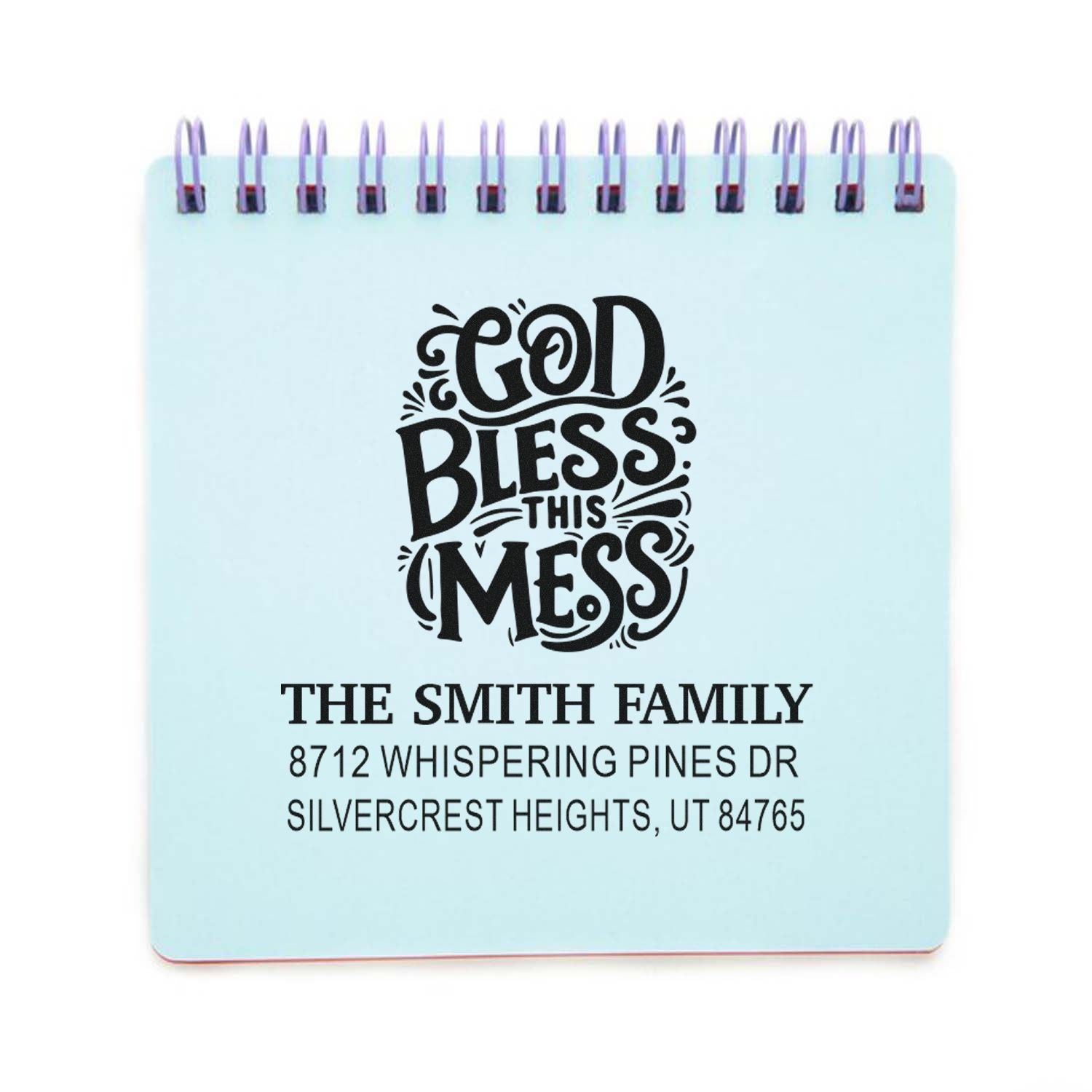Custom family address stamp with God Bless This Mess design, The Smith Family name, and Silvercrest Heights, Utah, shown on a spiral notebook mockup.