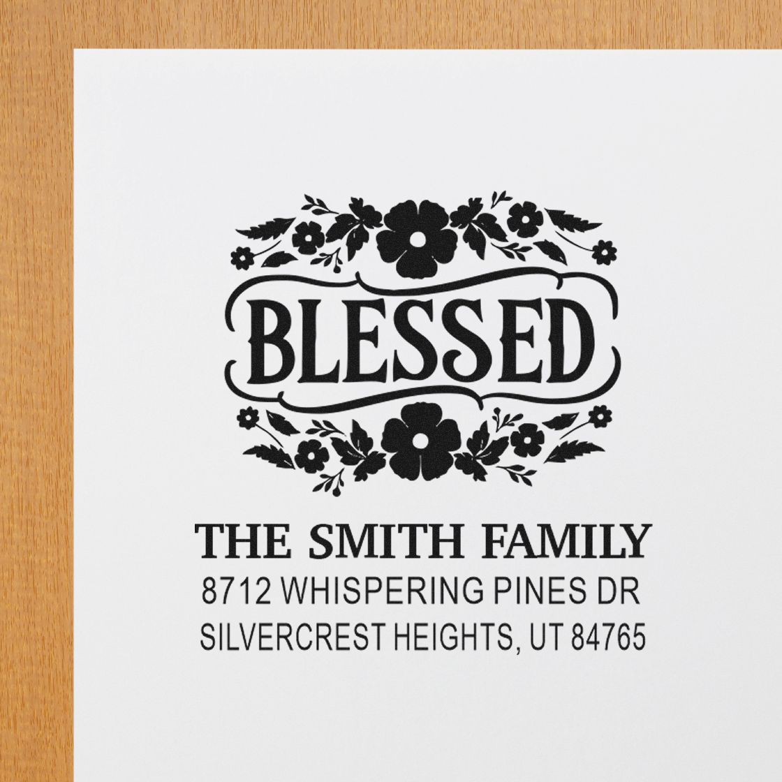 Personalized Blessed floral address stamp for The Smith Family with home address, shown in black ink on white paper over a wooden surface.