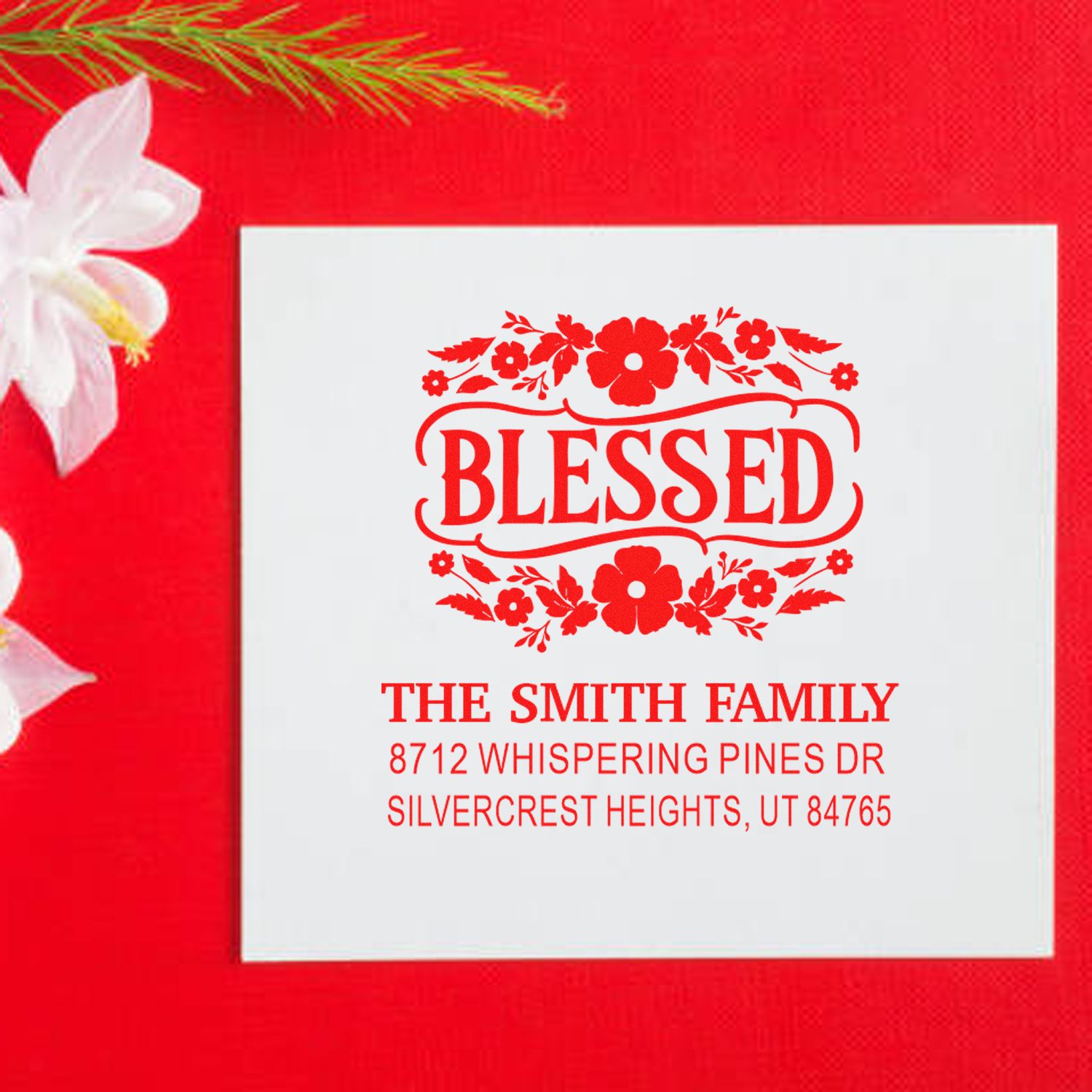 Custom Blessed address stamp for The Smith Family, with floral design and home address on a white card against a festive red background.
