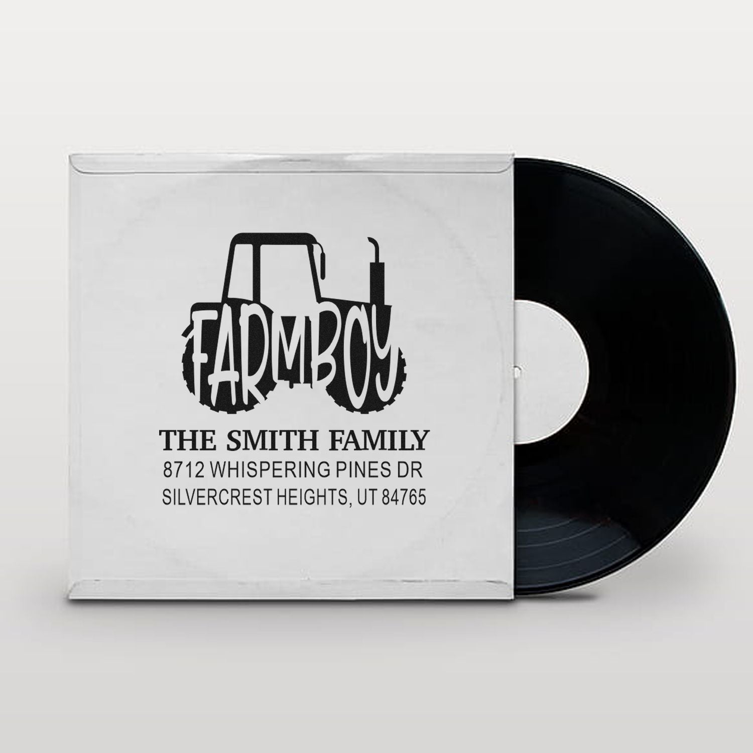 Custom Farmboy family address stamp with tractor design, The Smith Family name and address on a white mockup beside a black vinyl record.