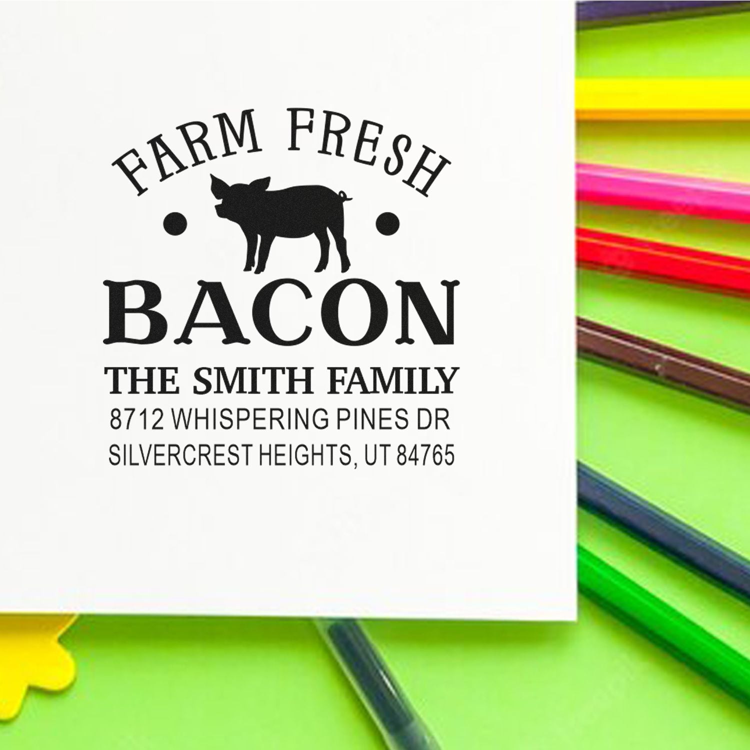 Custom farm fresh bacon address stamp with pig logo and Smith family address on white card beside colorful pens