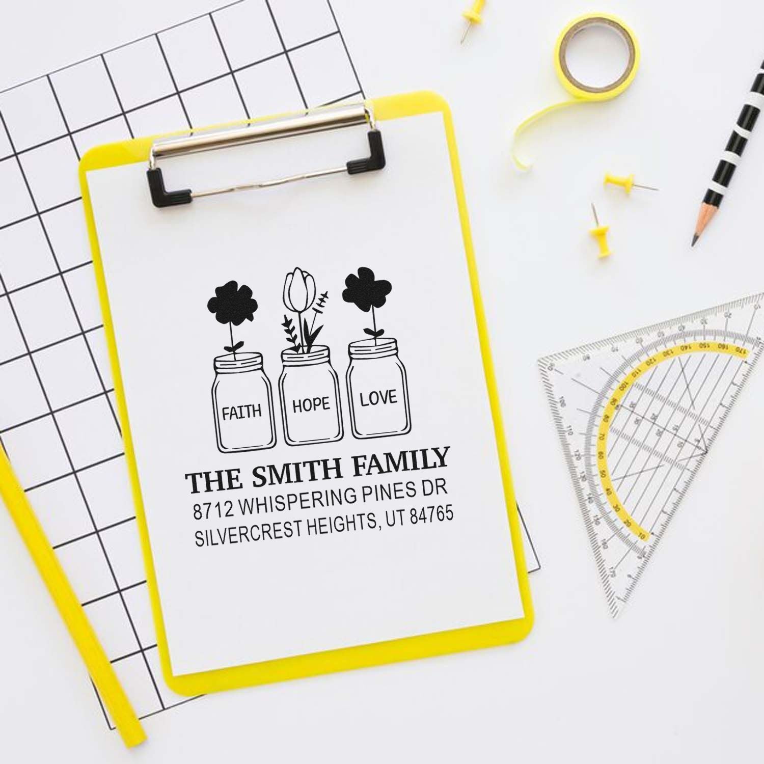 Personalized family address stamp set with faith, hope and love mason jars on a clipboard, styled with stationery, tape, pencil, and ruler.