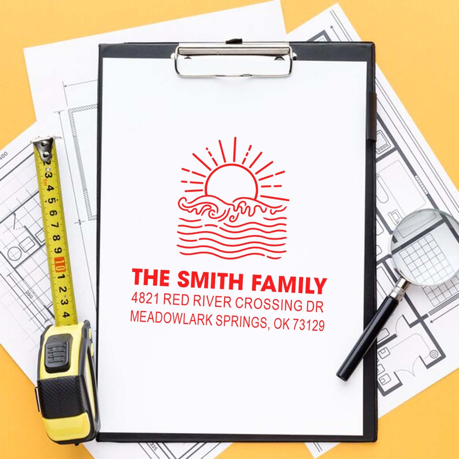 Custom family address stamp on clipboard with sun-and-waves design, surrounded by floor plans, tape measure and magnifying glass on yellow background.
