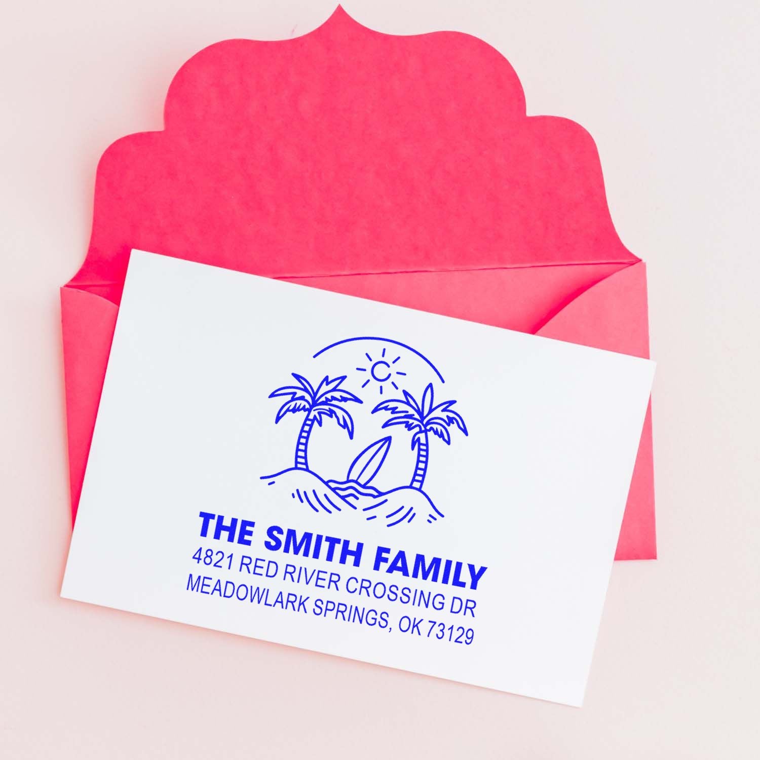 Custom return address stamp with tropical palm tree beach logo on a white card, displayed over a bright pink envelope.