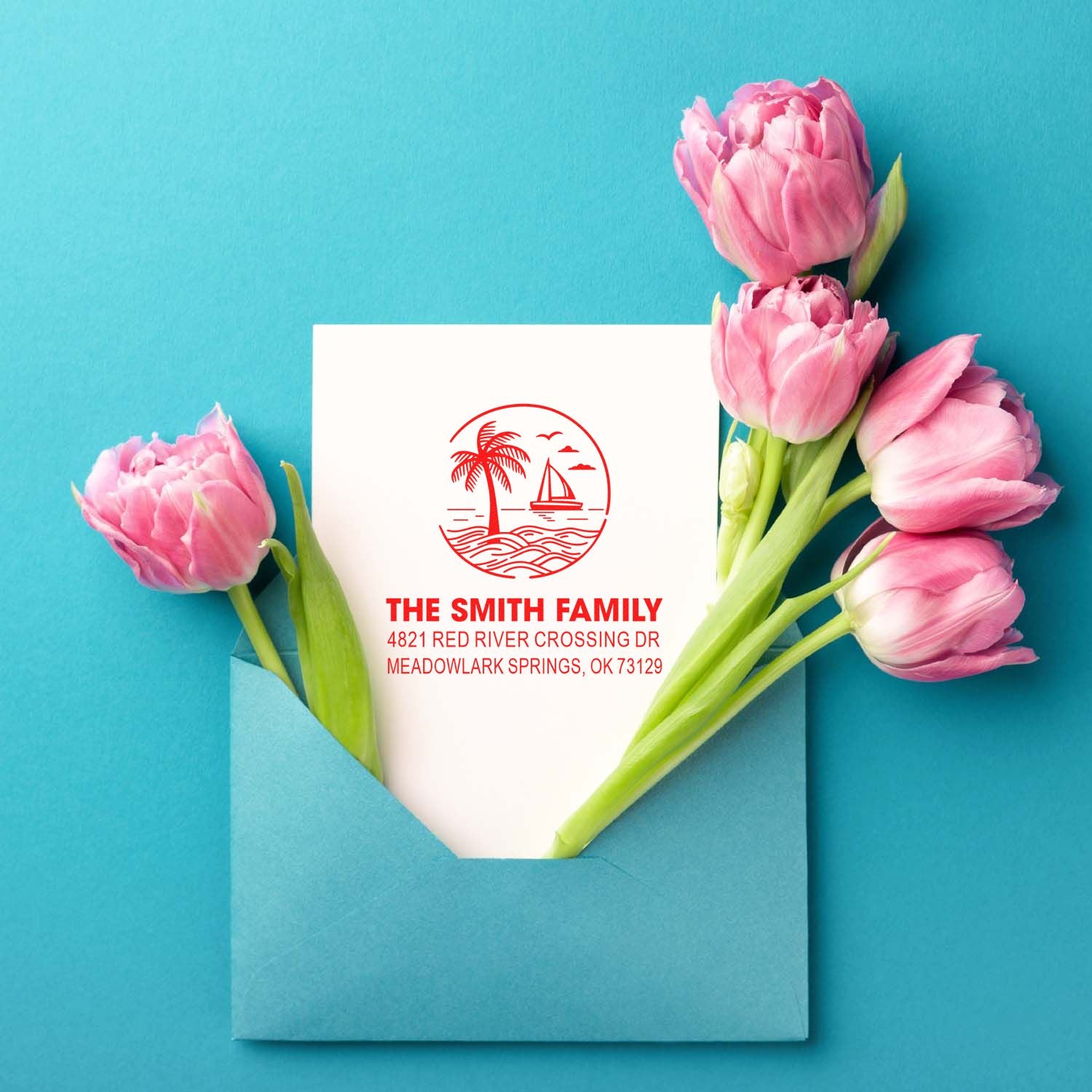 Custom family address stamp on white card in a blue envelope, framed by pink tulips on a turquoise background.