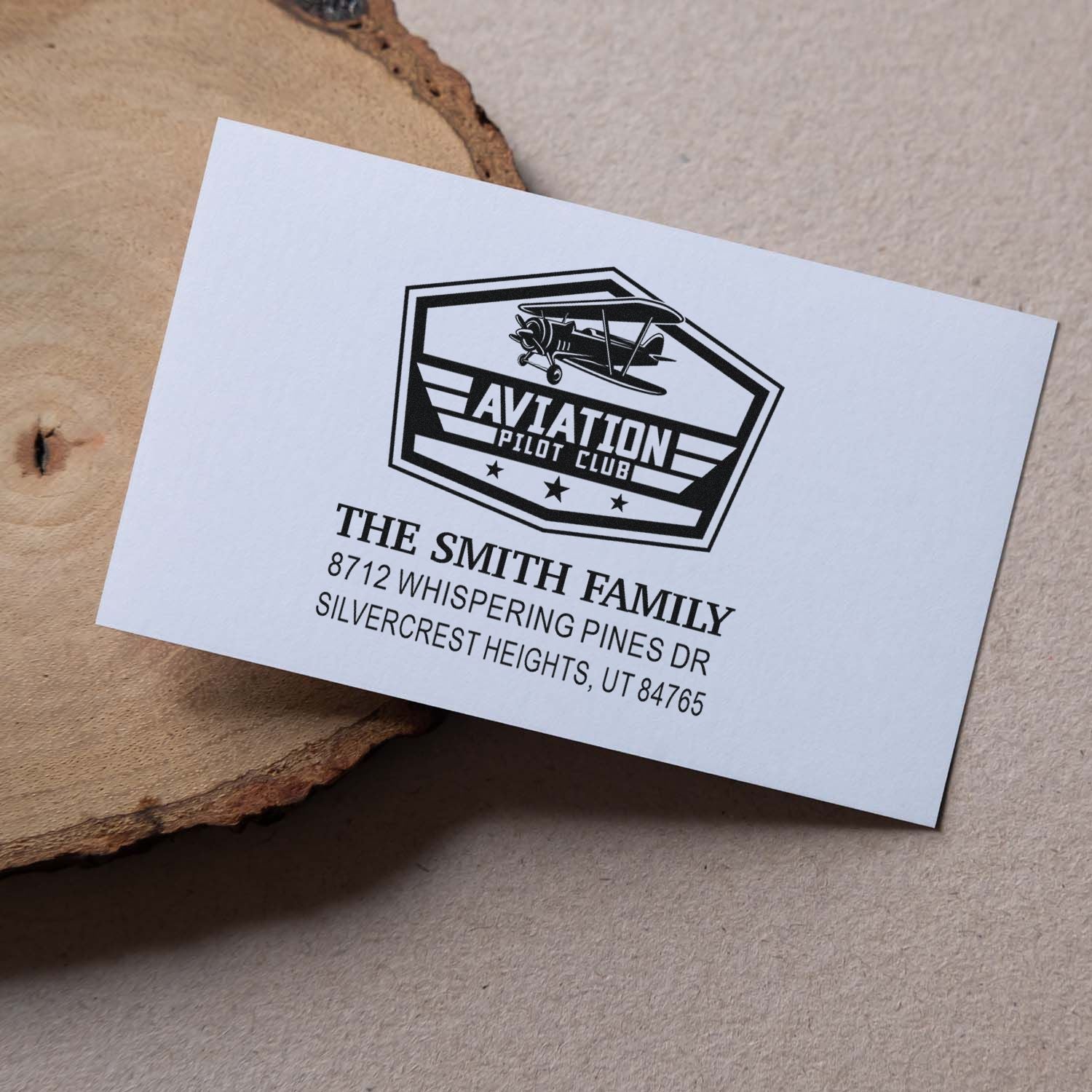 Custom aviation pilot club address stamp on white card, featuring biplane logo and Smith family return address on rustic wood background.