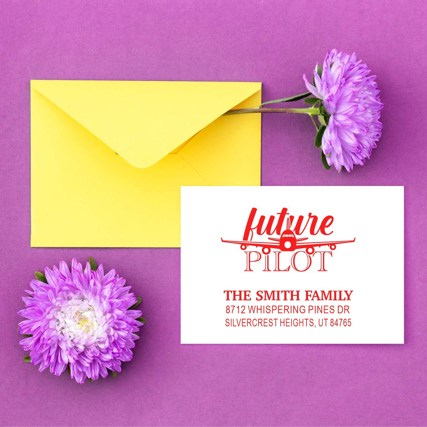 Custom rubber return address stamp with airplane and future pilot text beside a yellow envelope and purple flowers on a pink background.