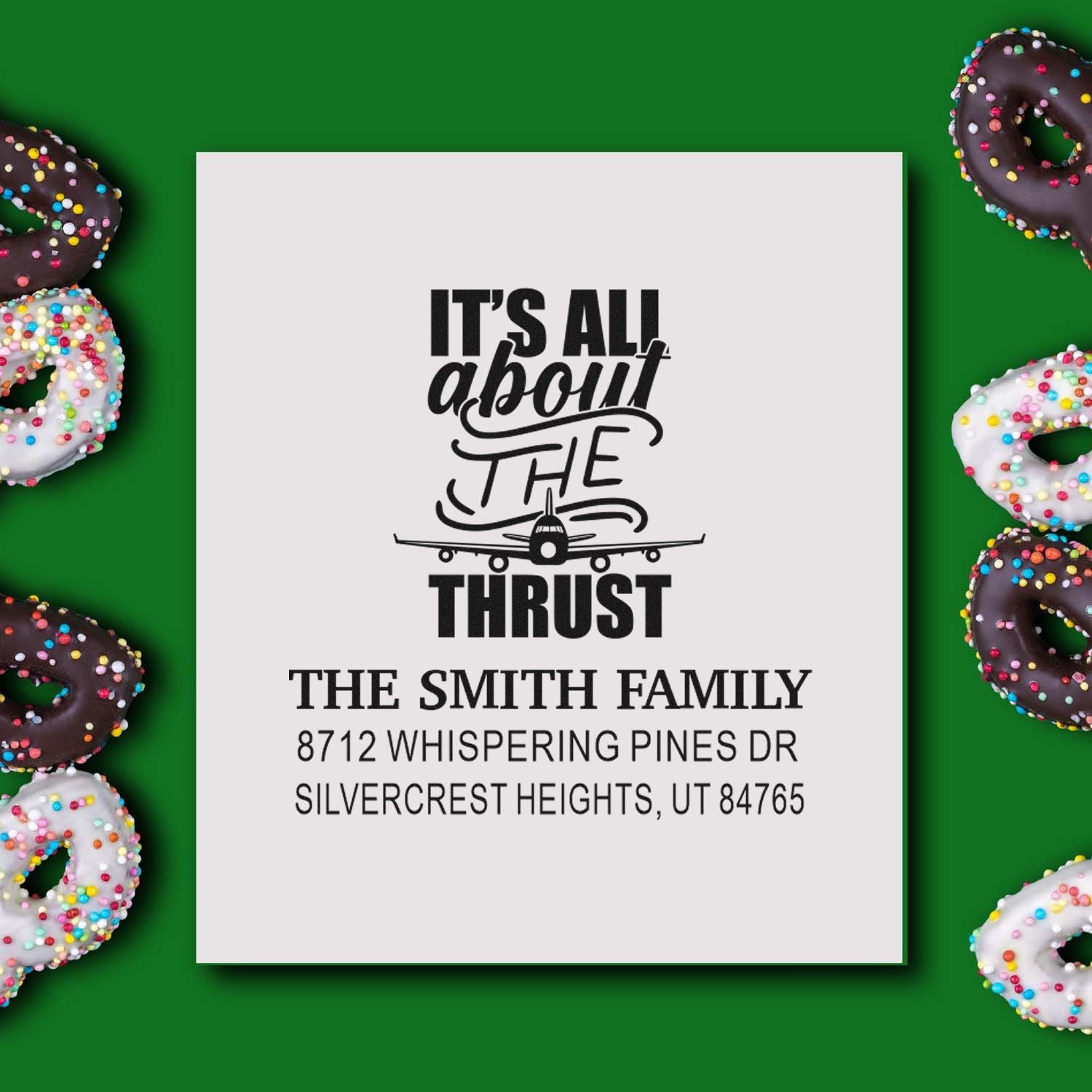 Custom address stamp with airplane and Its all about the thrust slogan, on green background with sprinkled donuts.