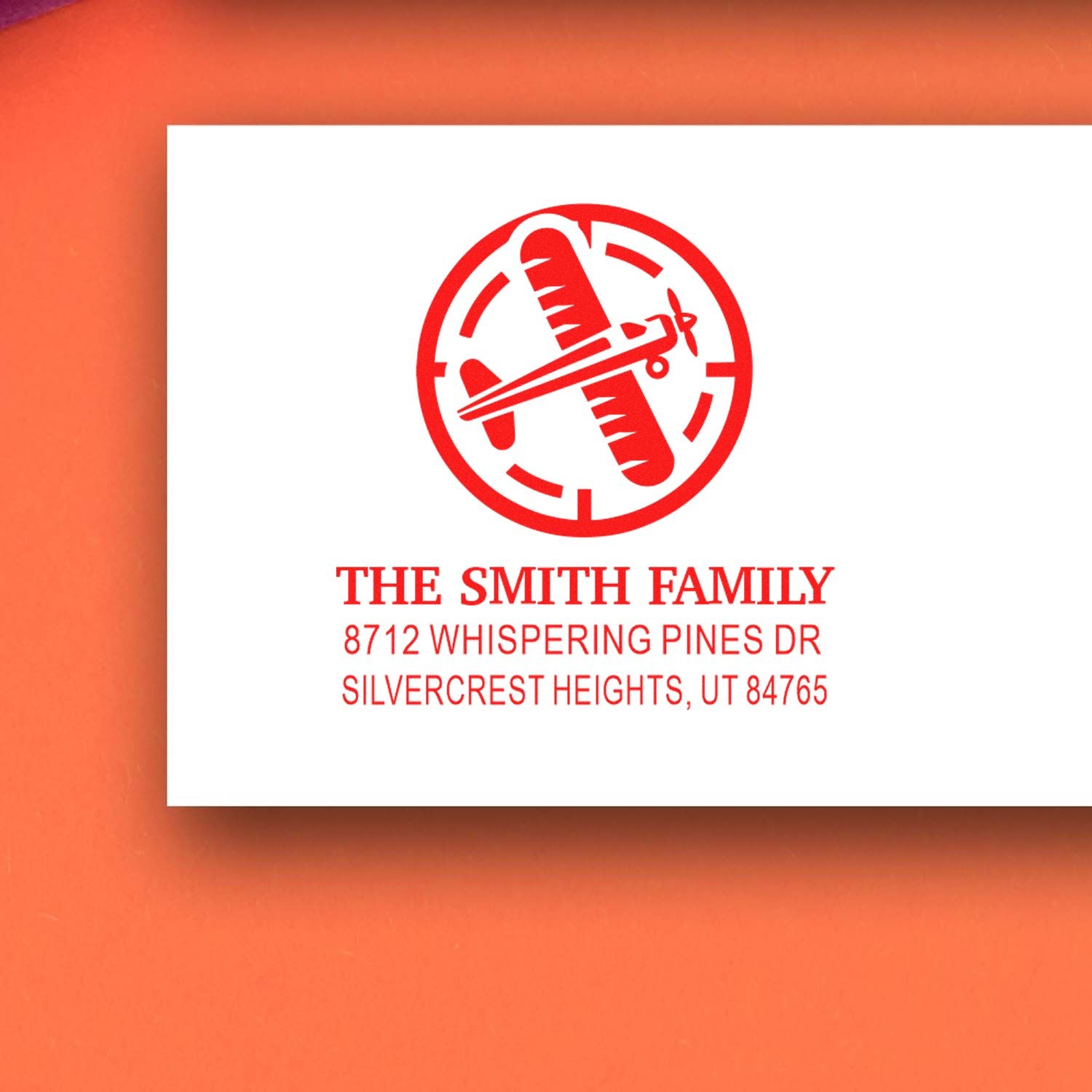 Custom red return address stamp with airplane and passport motif for The Smith Family, shown on a white card against an orange background.