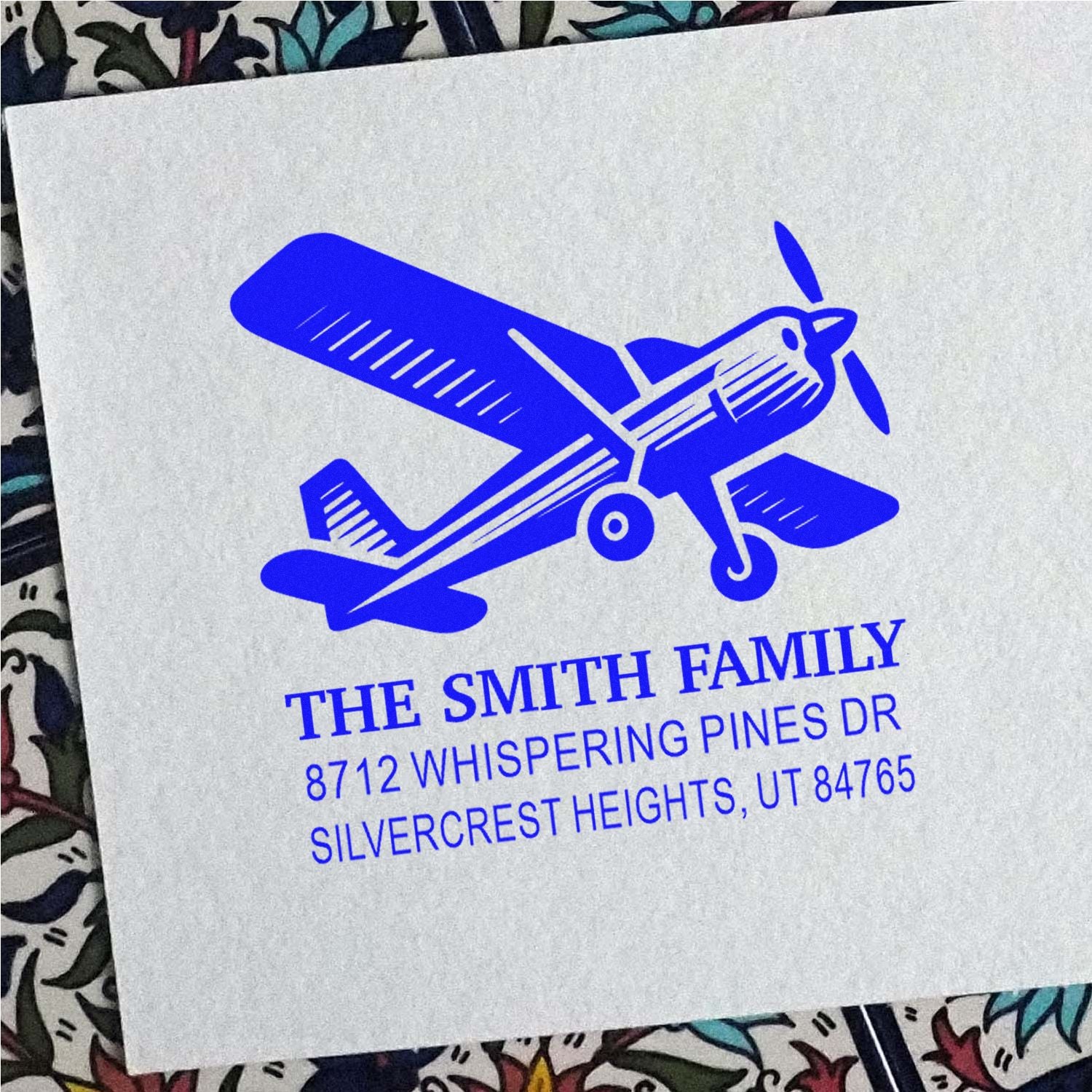 Blue custom airplane address stamp for The Smith Family on white paper, with 8712 Whispering Pines Dr, Silvercrest Heights, UT.