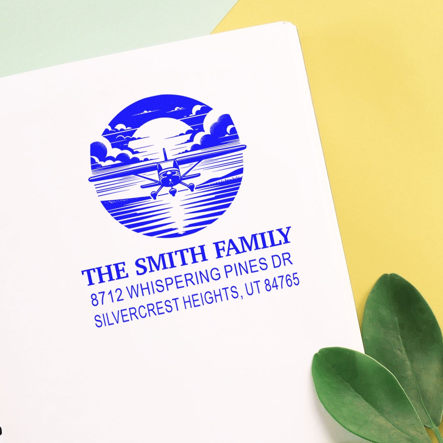 Custom family address stamp for The Smith Family with blue airplane design on white paper, styled on a yellow background with green leaves.
