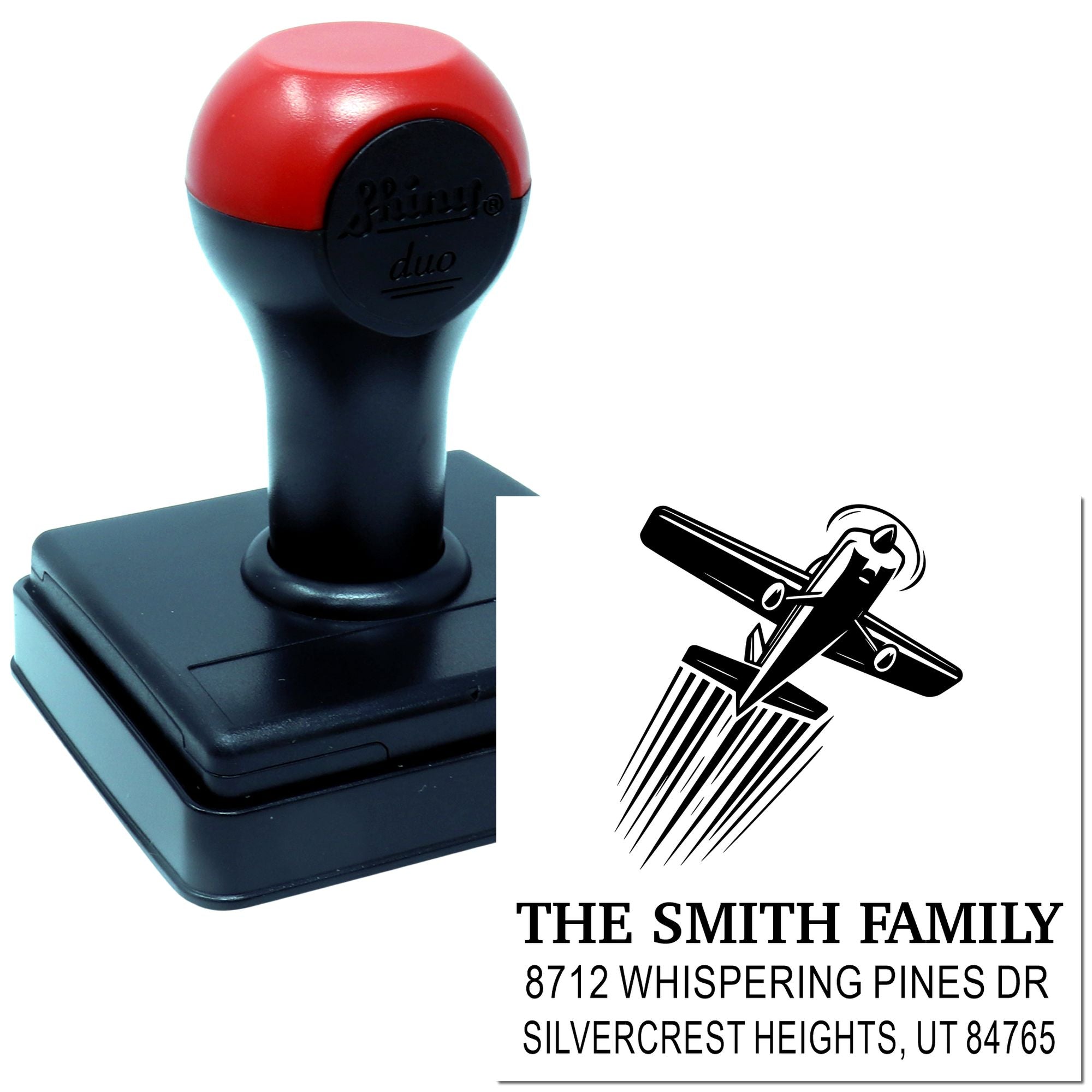 Custom self-inking address stamp with red and black handle, showing family name, address, and logo design on a white background.