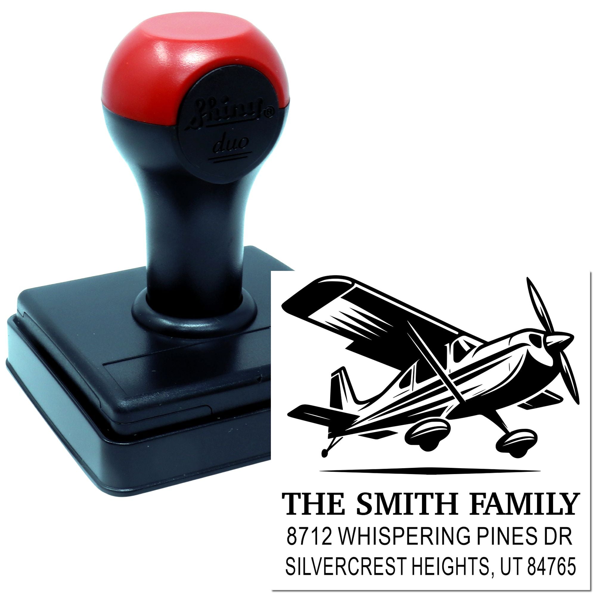 Custom self-inking address stamp with airplane logo, black base, and family name on white background for mailing and personal use.