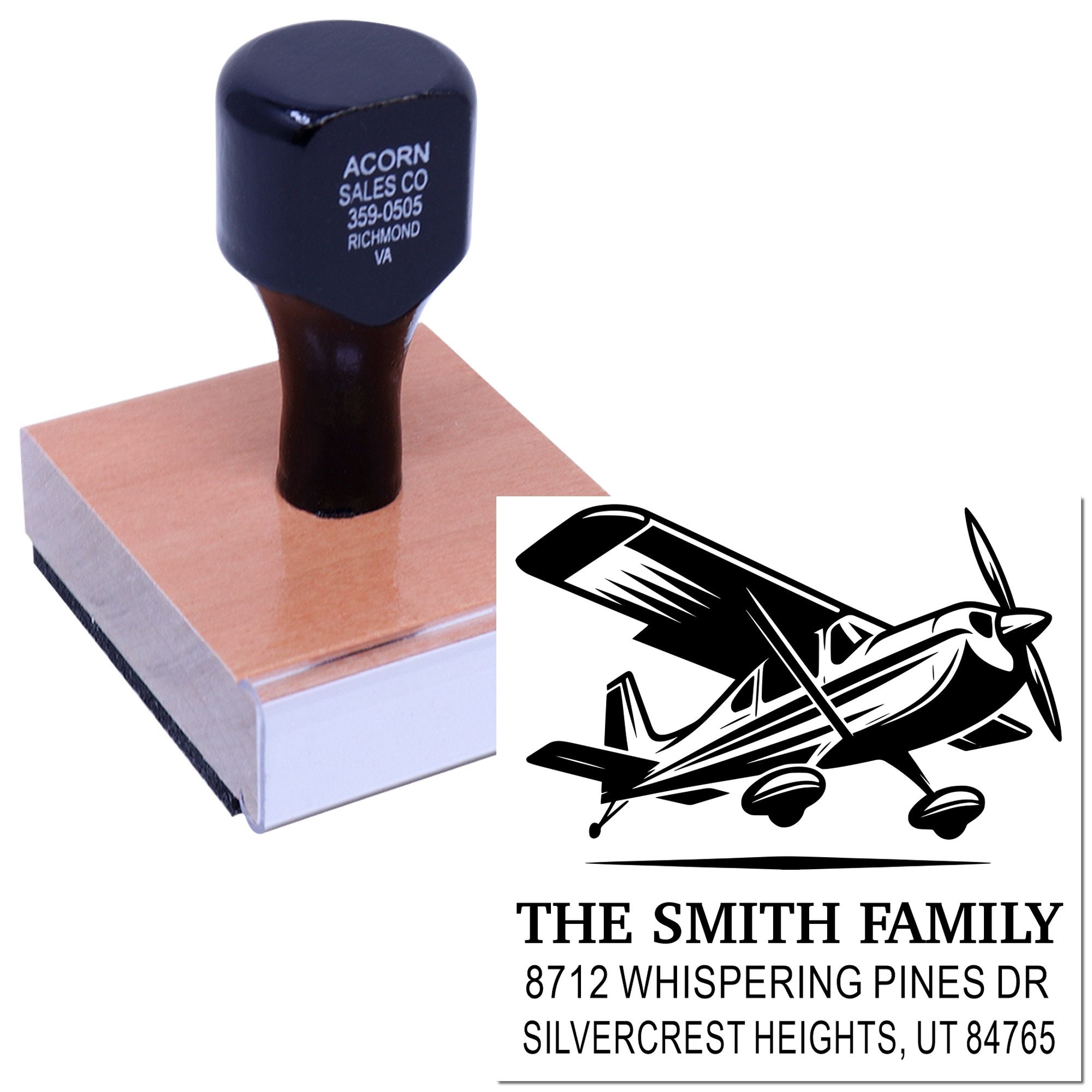 Personalized address stamp with airplane design, shown on a wooden base beside a printed family mailing address on a white background.
